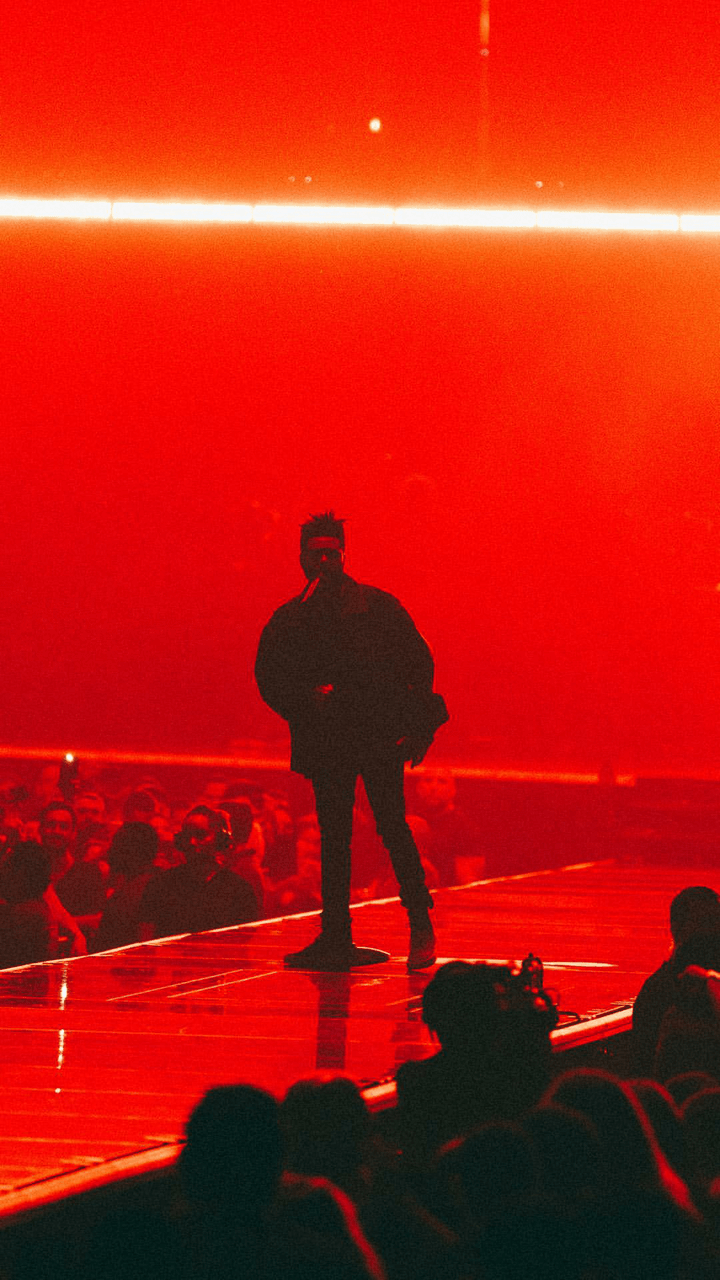 The Weeknd performs on stage in front of a red background - The Weeknd