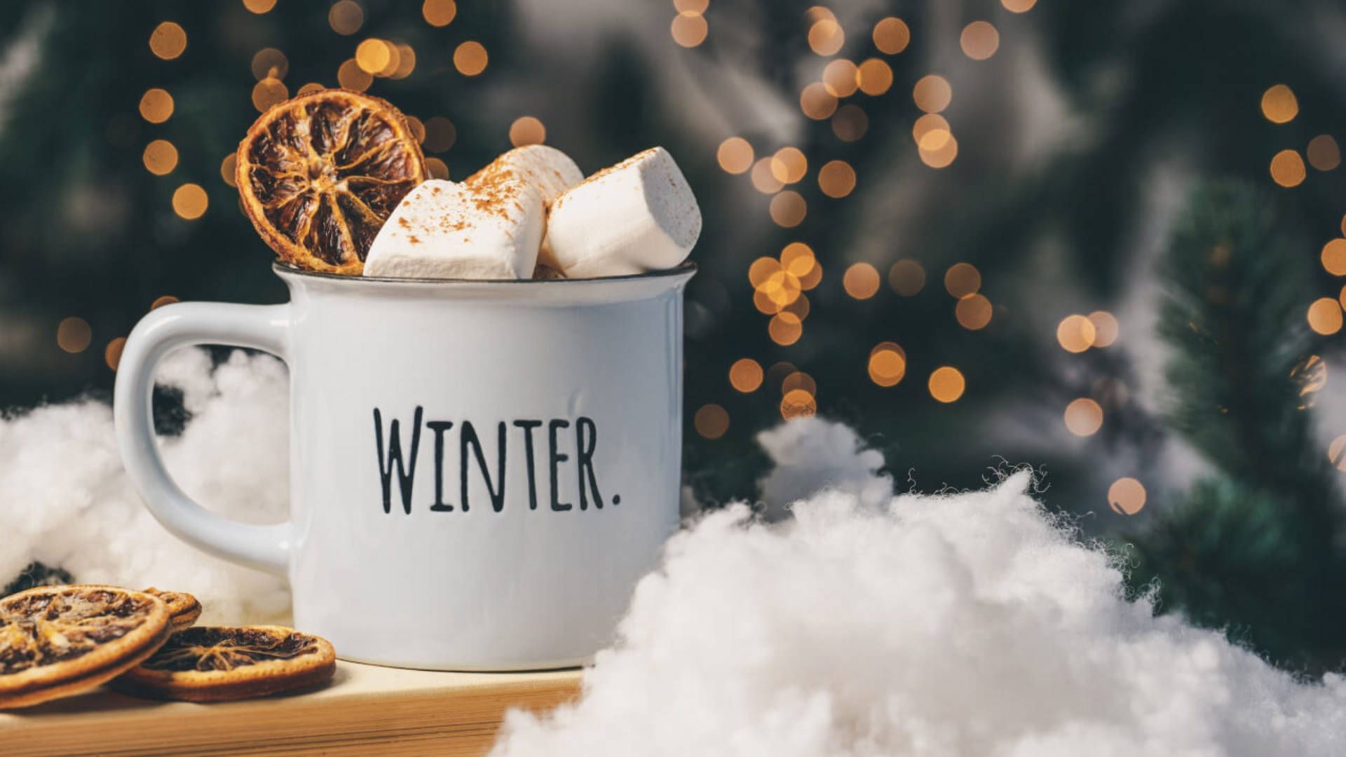 A mug with marshmallows and oranges on top of snow - Winter, cozy
