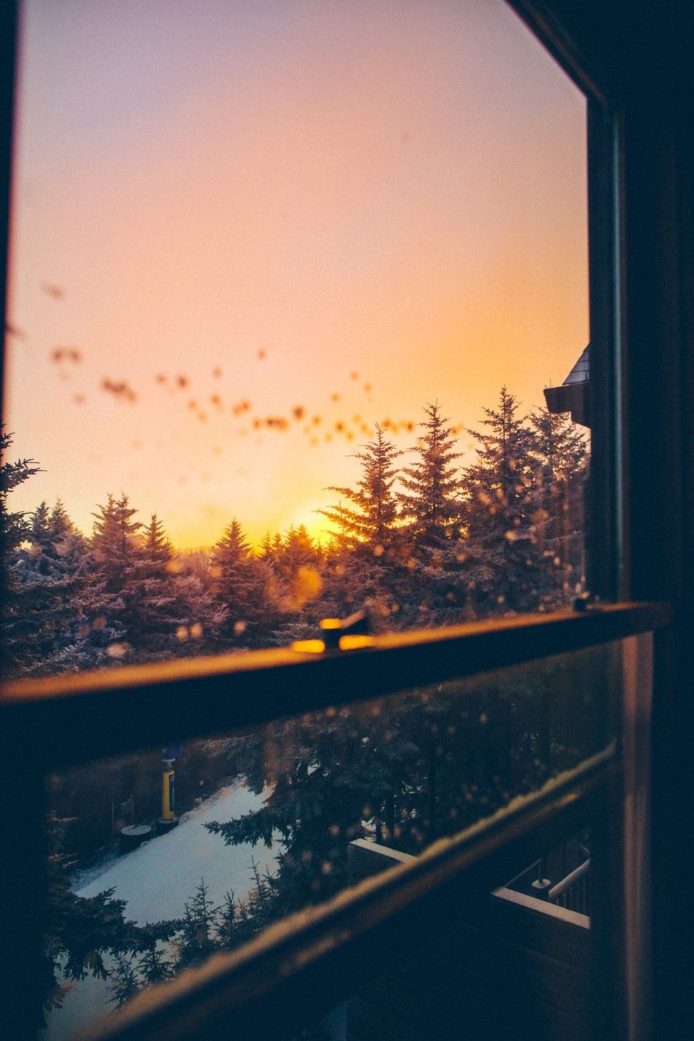 A beautiful sunset over a snowy forest, as seen through a window. - Warm, cozy