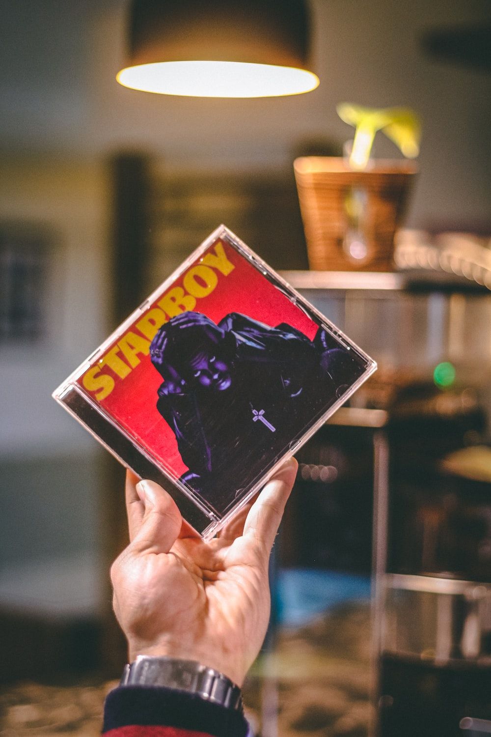 A person holding up an album cover - The Weeknd