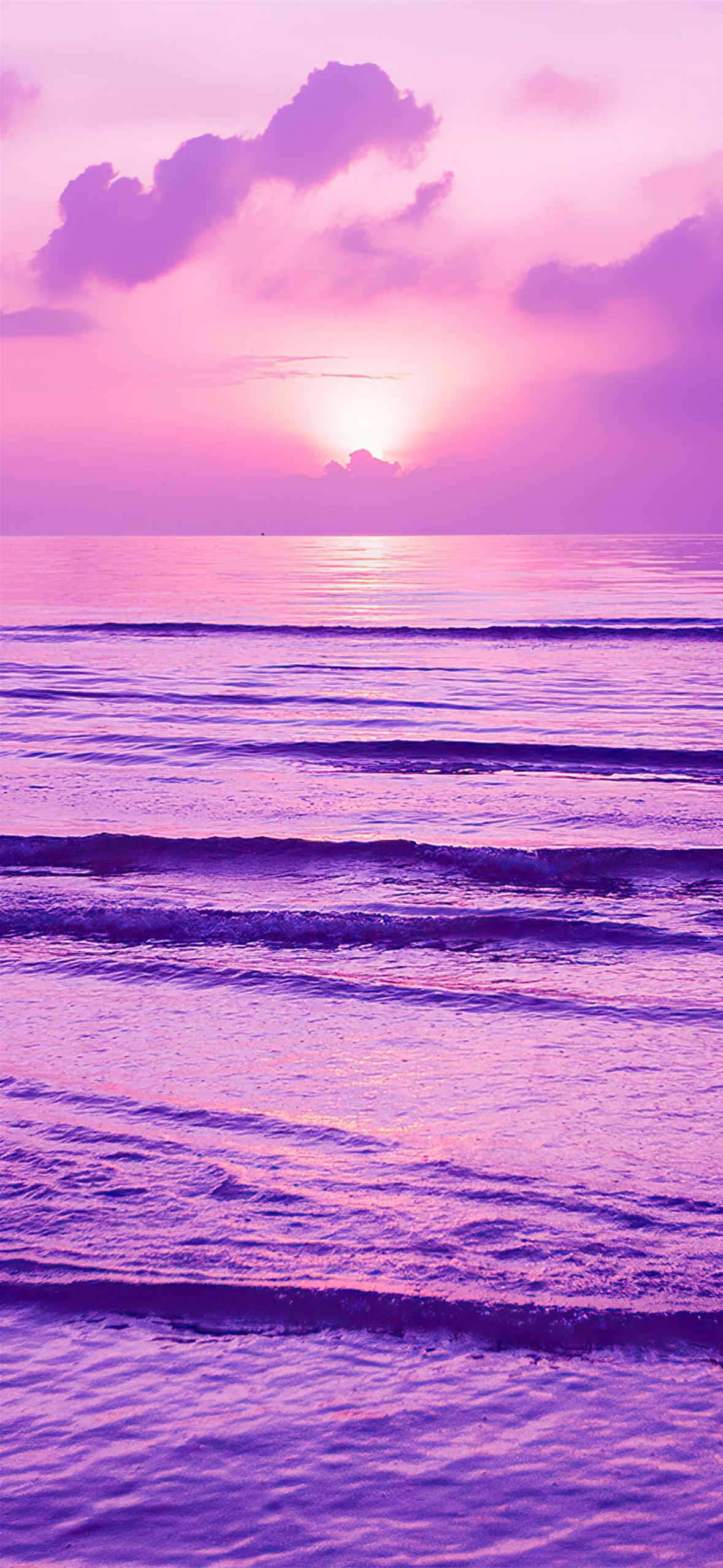 A surfer riding the waves in front of an orange and purple sky - Sunset