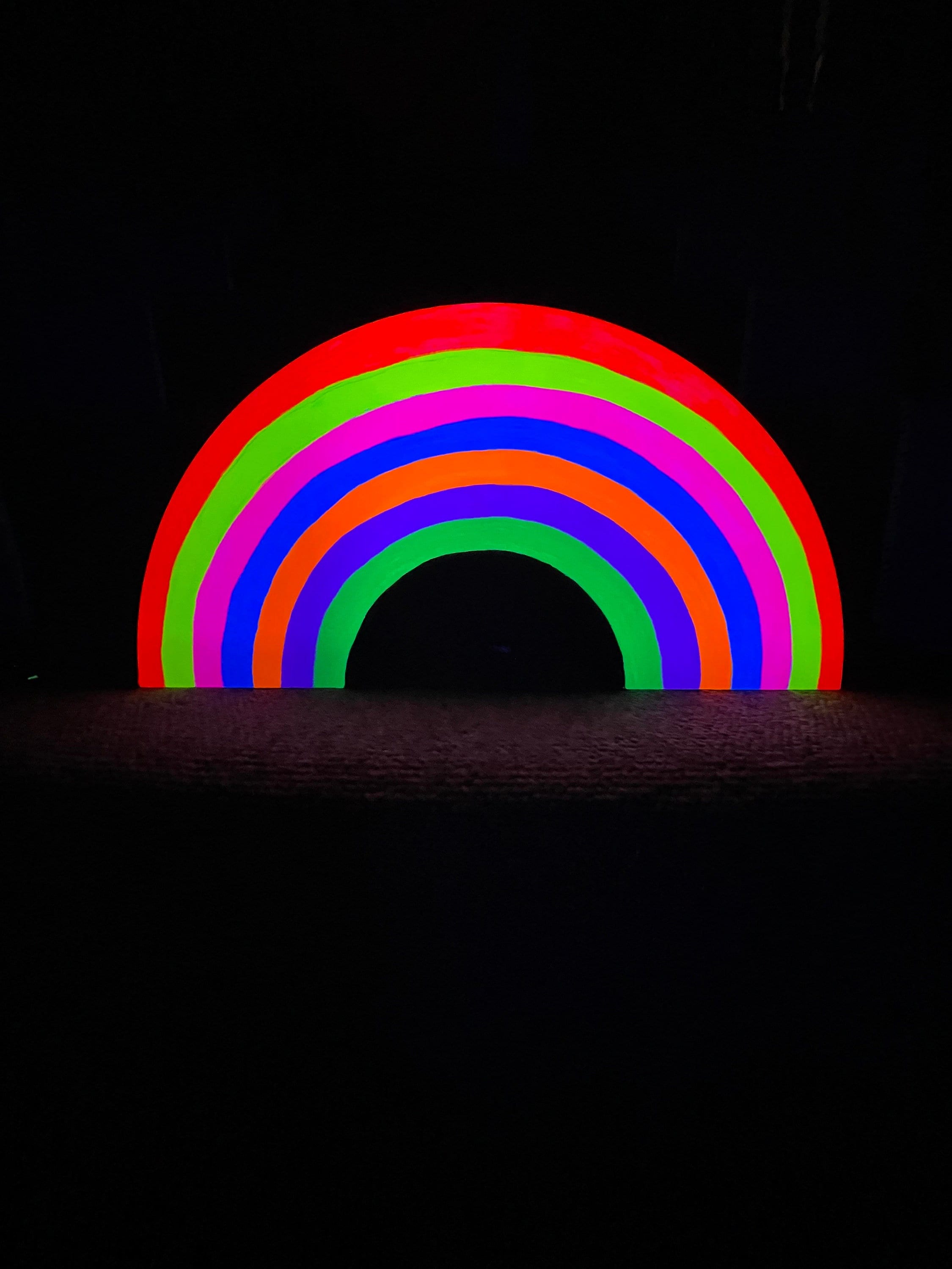 A neon rainbow sign on a black background. - Pride