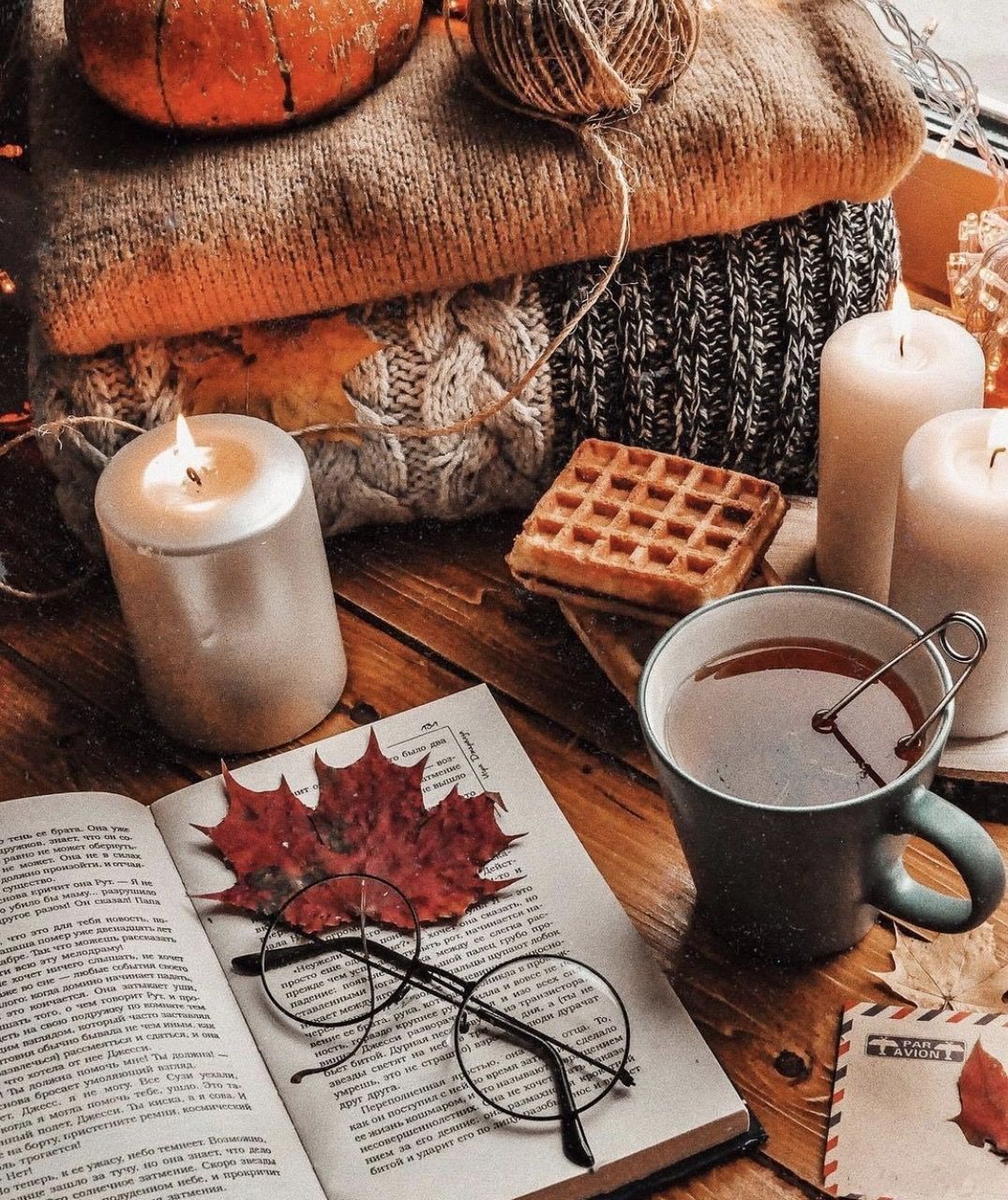 A book, a cup of tea, a candle, a leaf, a pair of glasses, and a waffle - Cozy