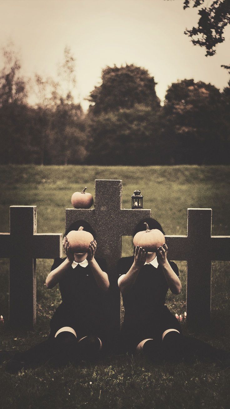 Two people dressed as ghosts sitting on top of graves - Creepy