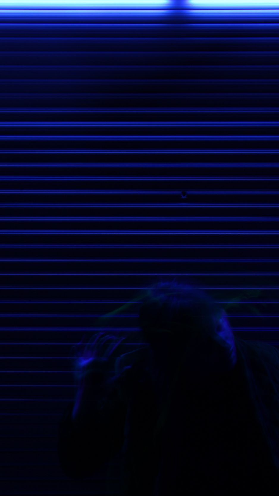A person standing in front of a wall with blue lights. - Creepy
