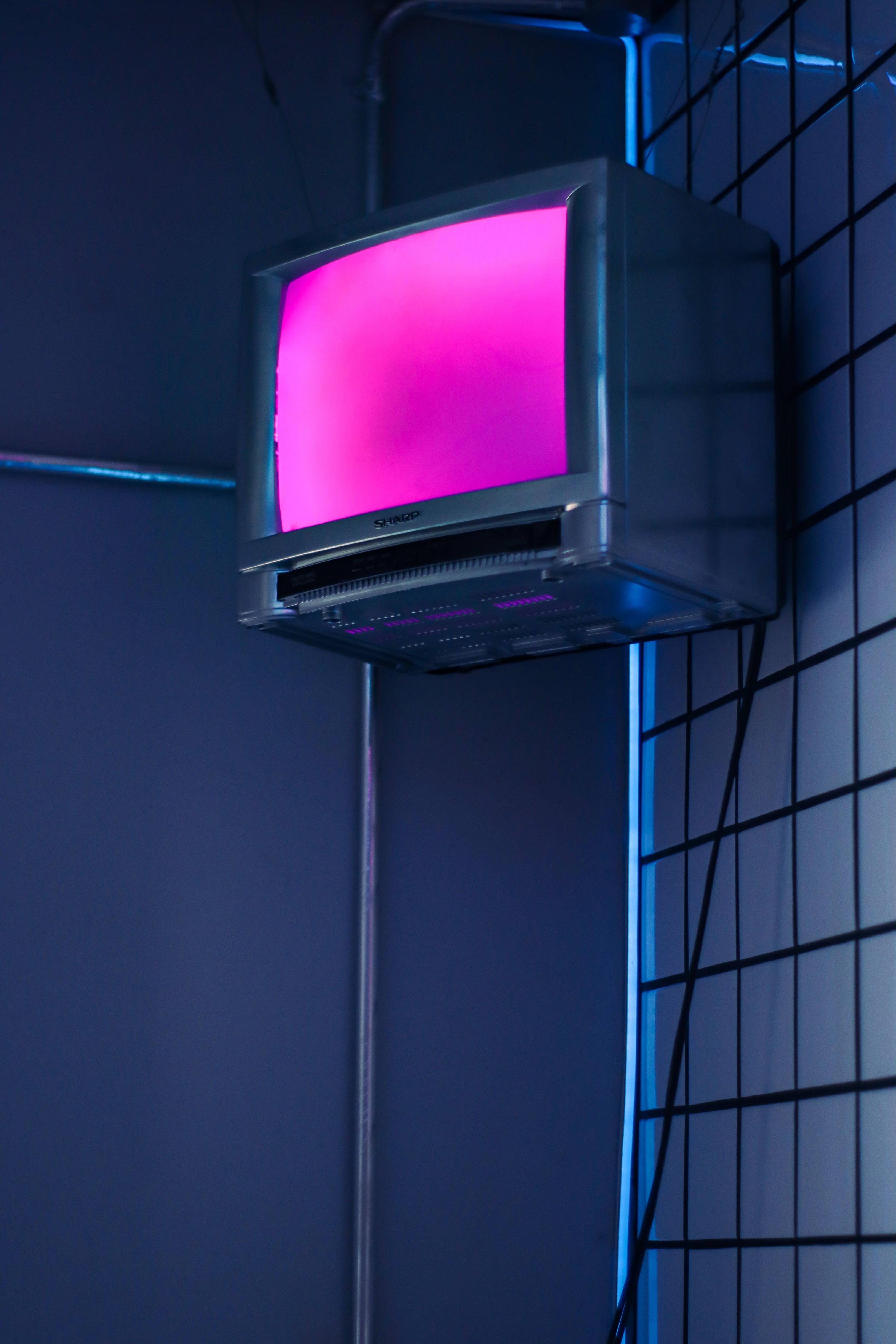 A television set with a pink screen is hanging on a wall. - Dark blue