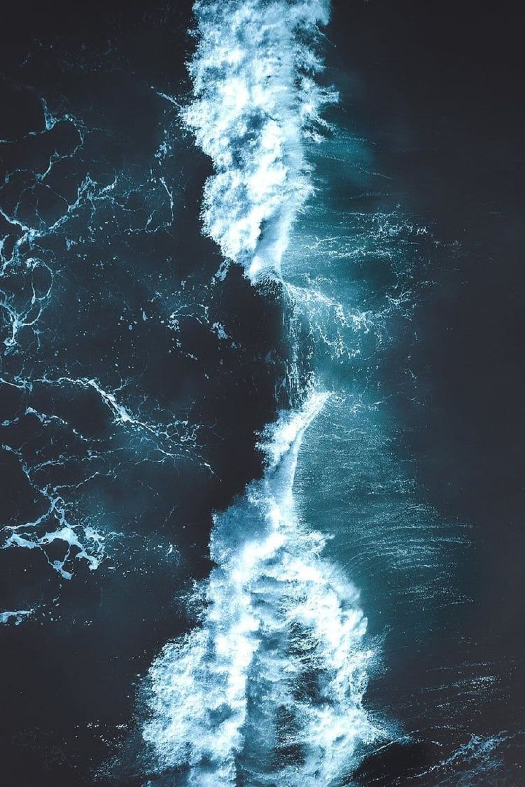 An aerial view of a wave breaking on the ocean - Navy blue, dark blue