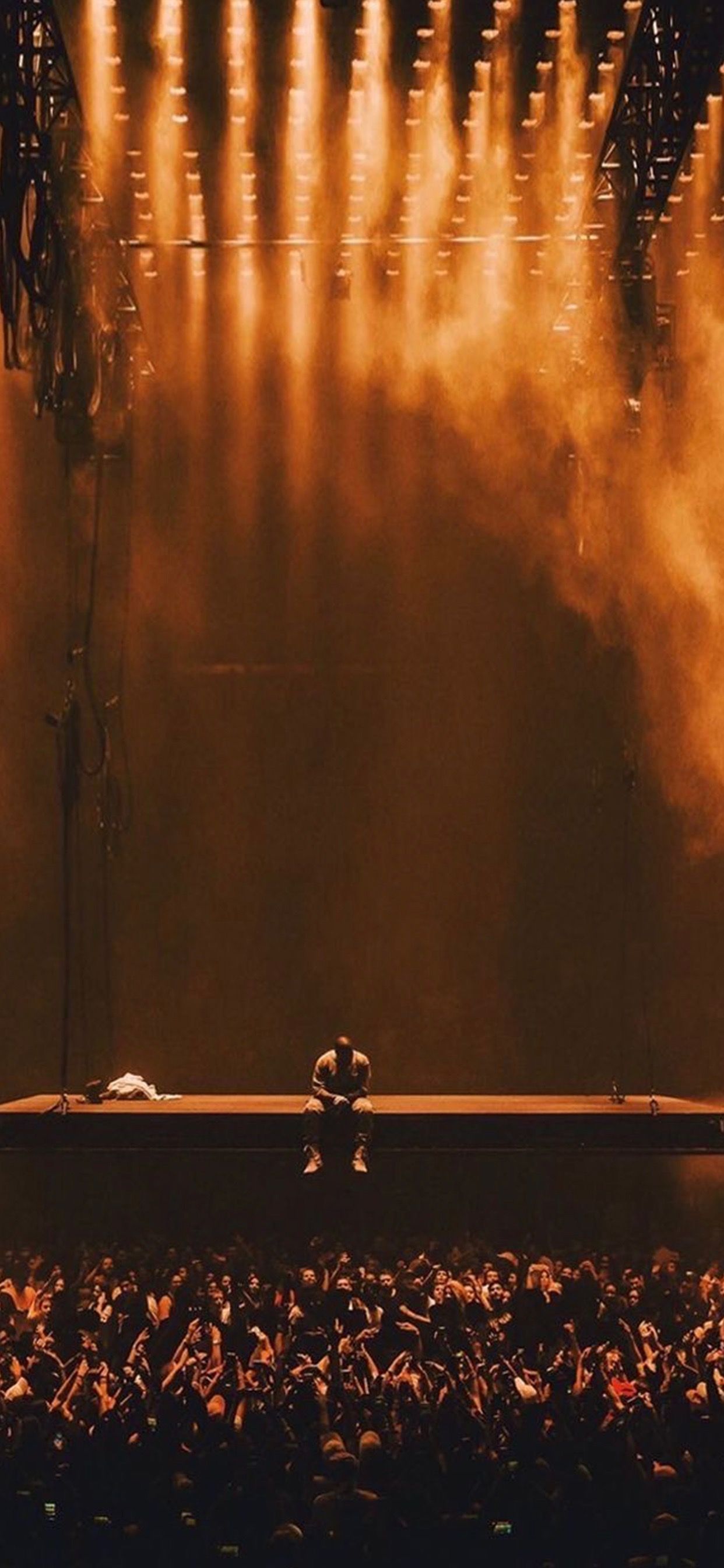 A person sitting on stage in front of an audience - Kanye West