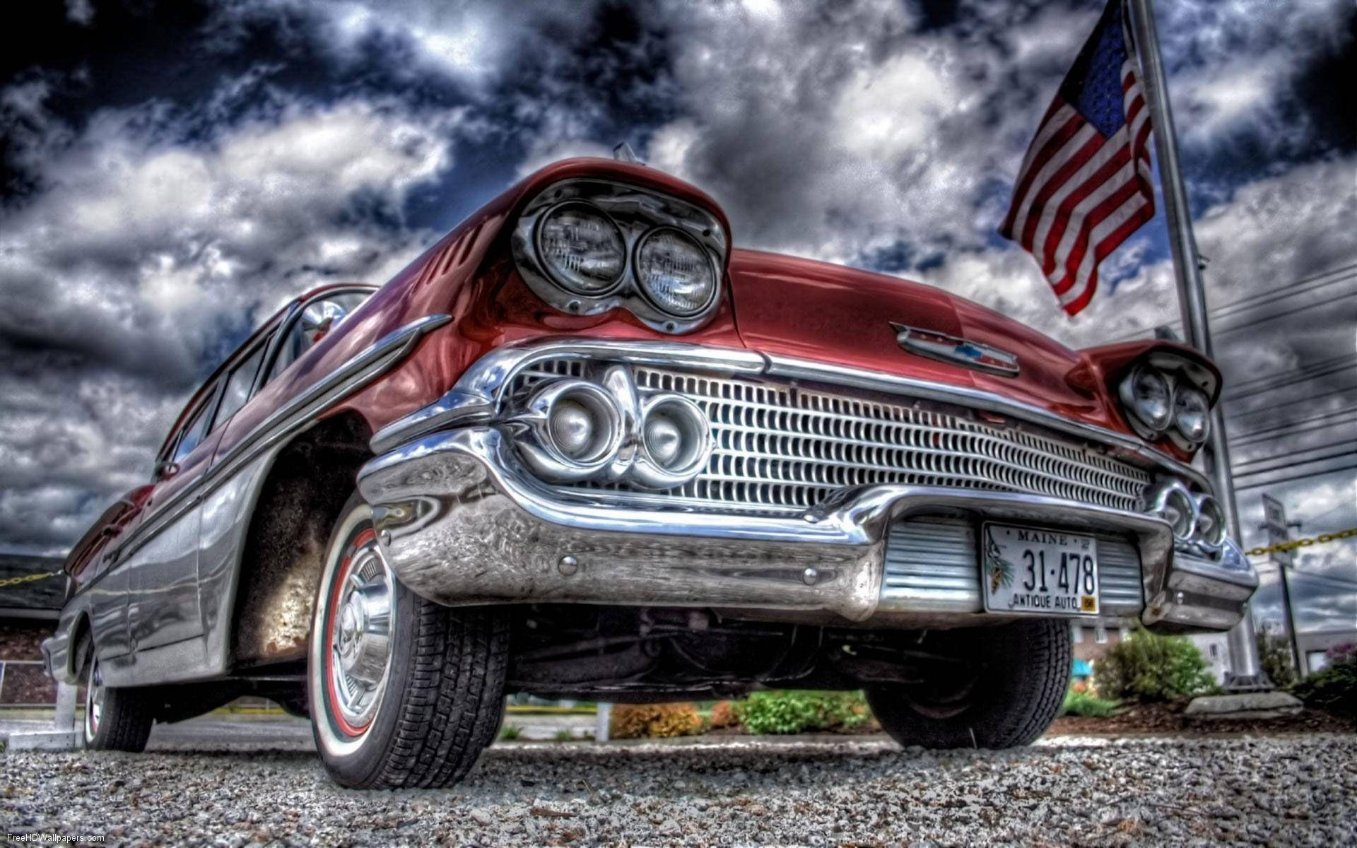 A classic car is parked in front of an american flag - 60s