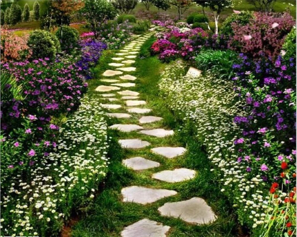 This image shows a garden path made of stones surrounded by colorful flowers. - Garden