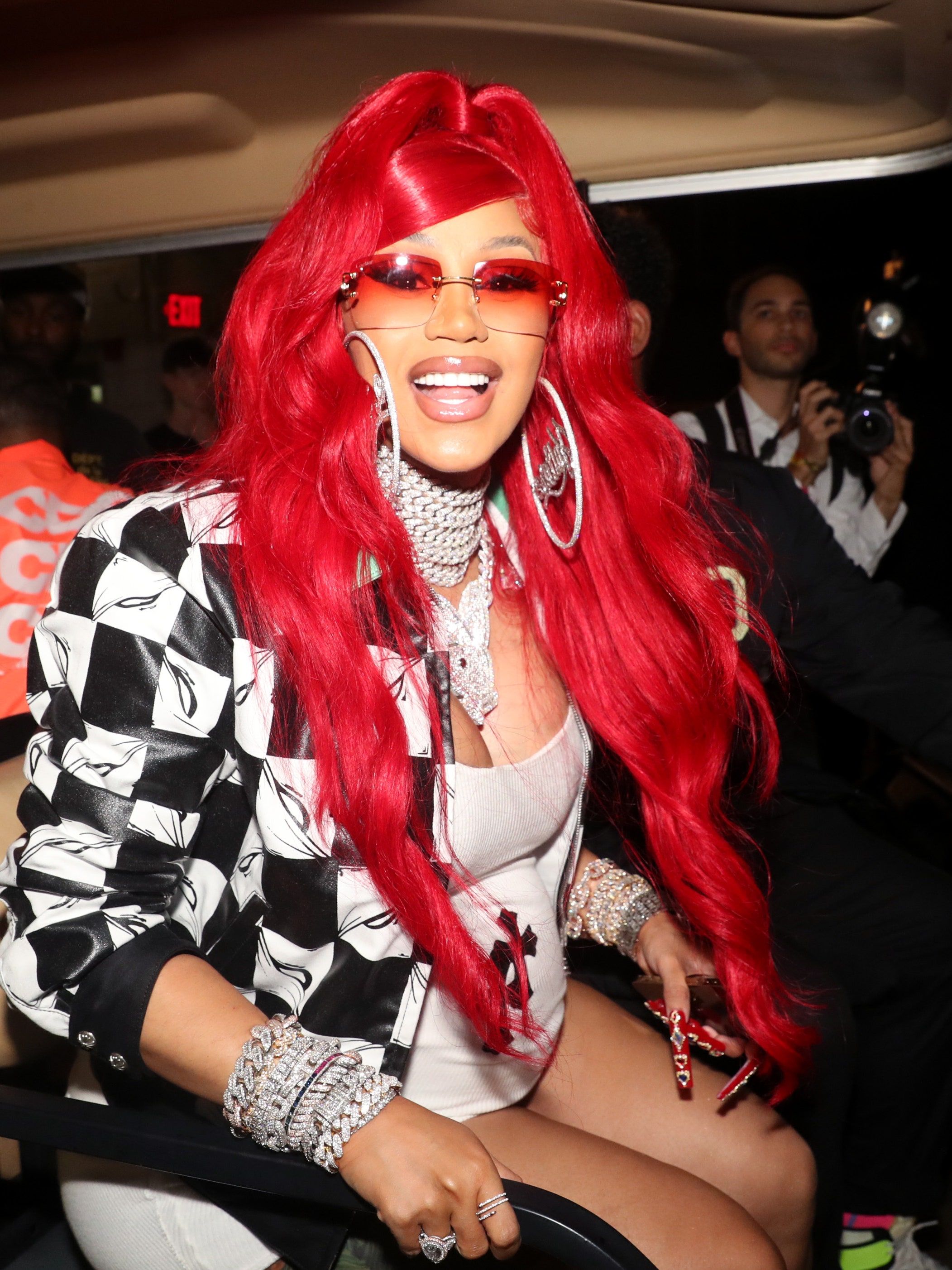 Cardi B in a red wig and sunglasses at an event. - Cardi B