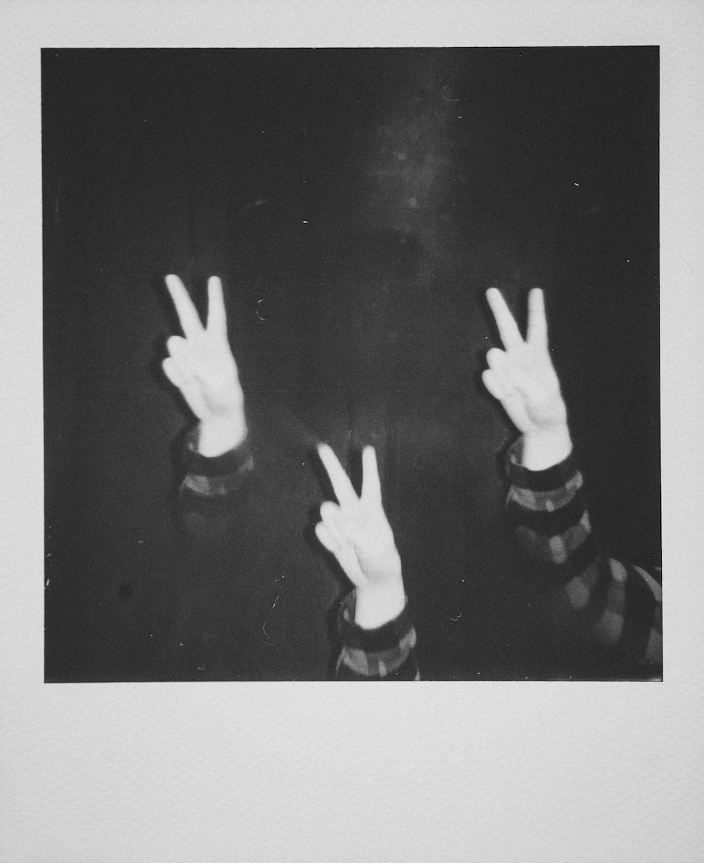 A black and white photograph of two hands making the peace sign - 90s