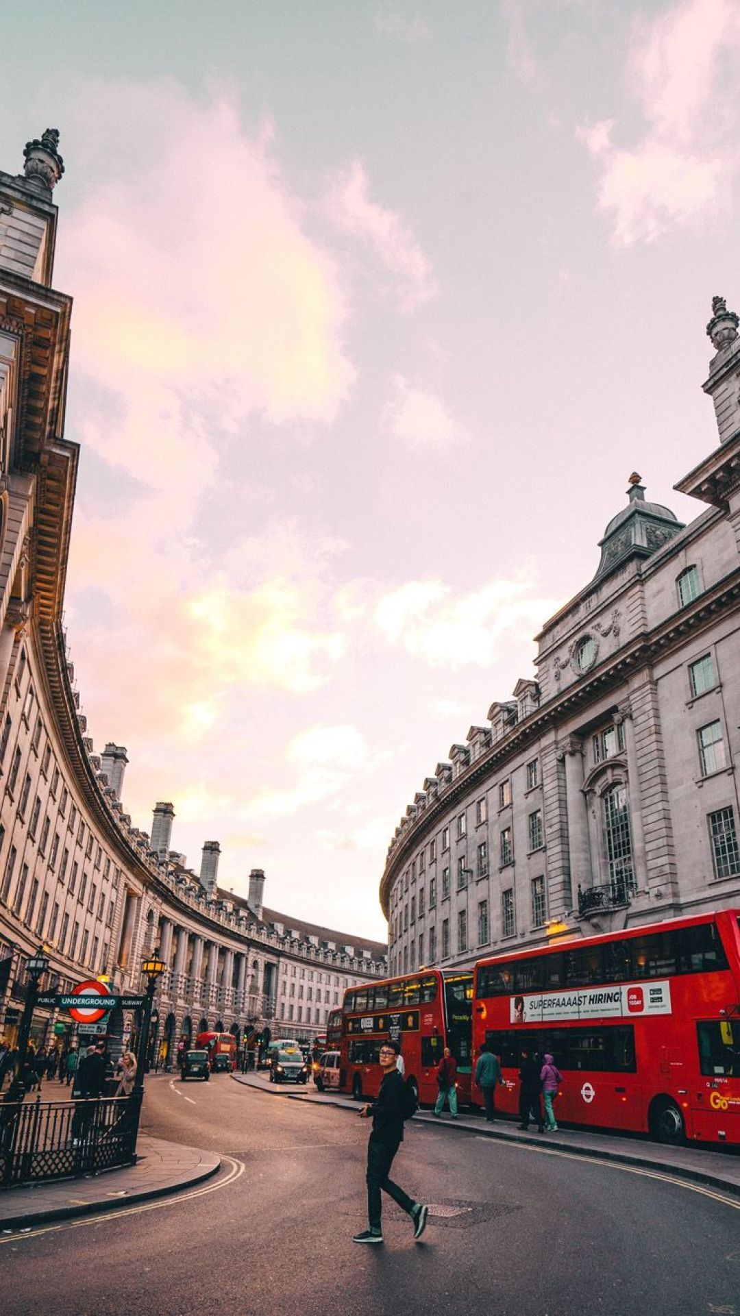 A person crossing the street in front of a red double decker bus. - London