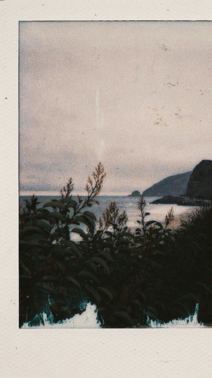 Polaroid of a body of water with a hill in the background - Polaroid