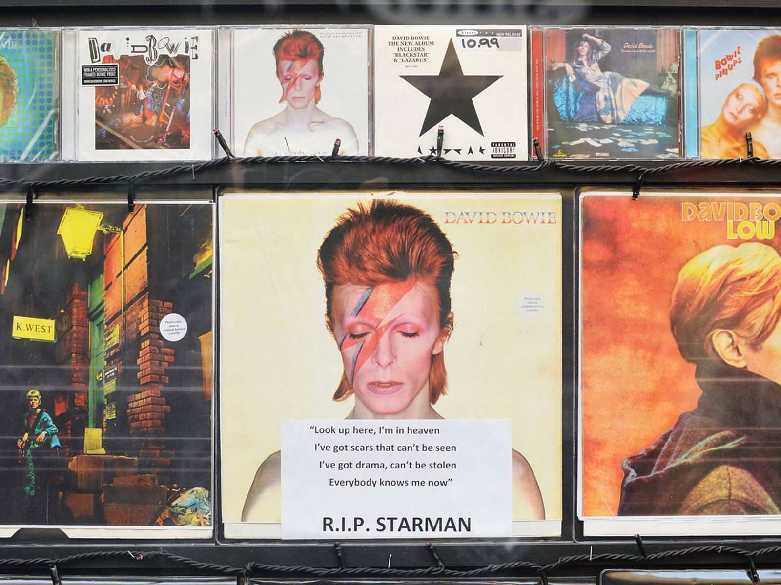 A shop window displays a sign in memory of David Bowie. - David Bowie