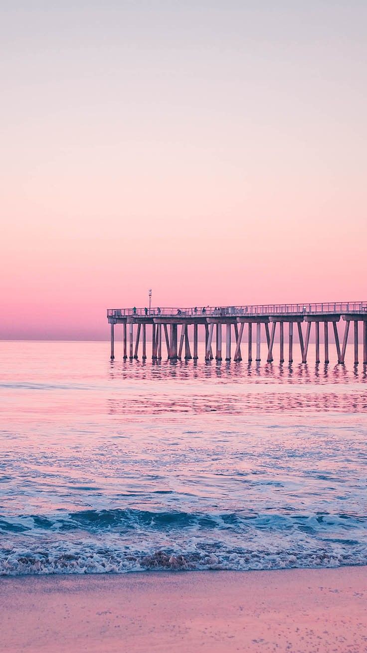 A pier in the distance with a pink and purple sky above it - Summer, beach
