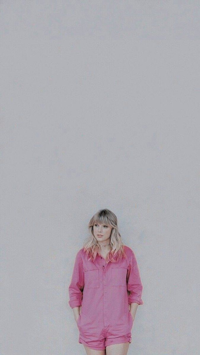 A woman in pink shorts and shirt standing on the sidewalk - Taylor Swift