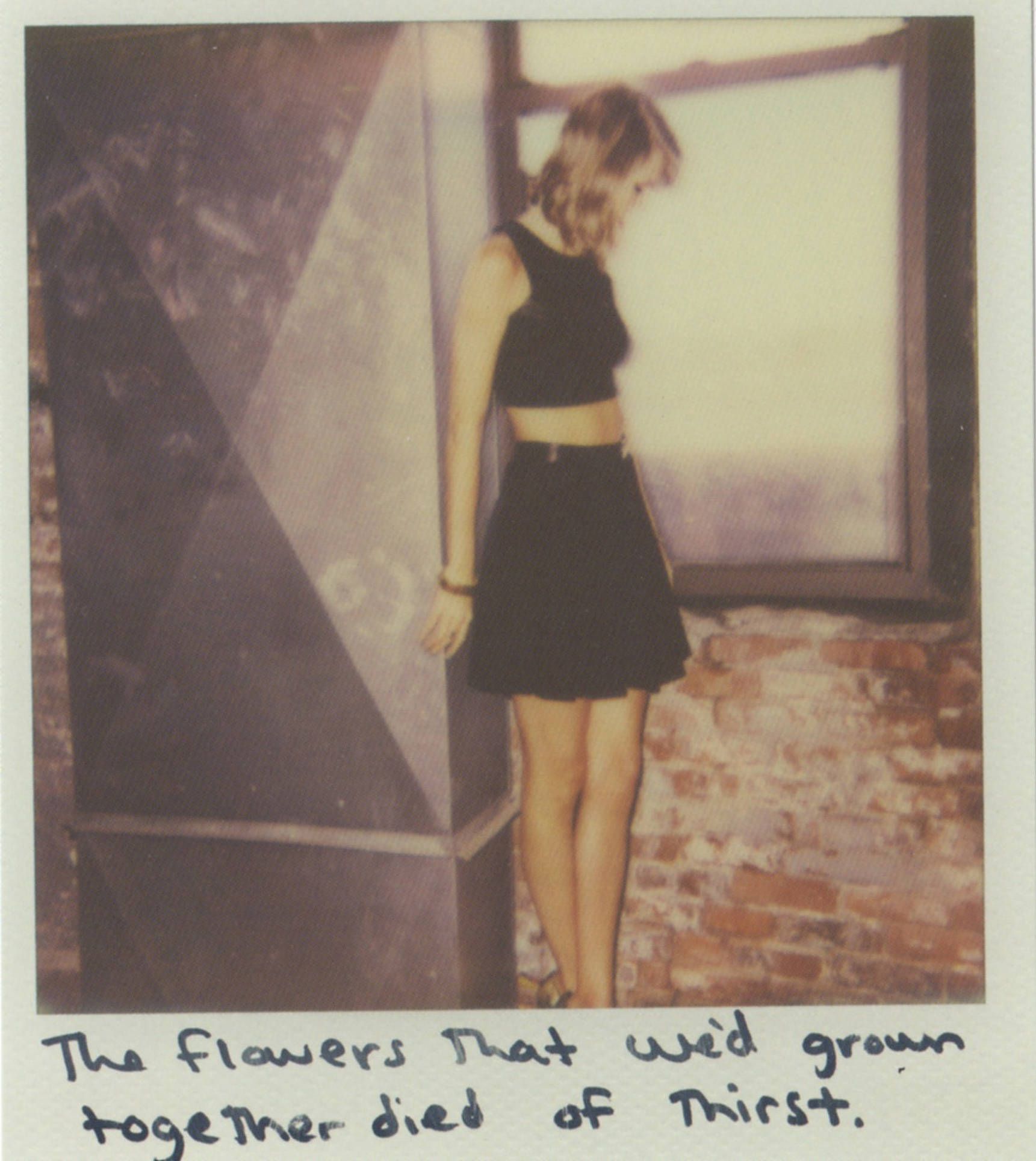 A woman standing next to brick wall - Taylor Swift