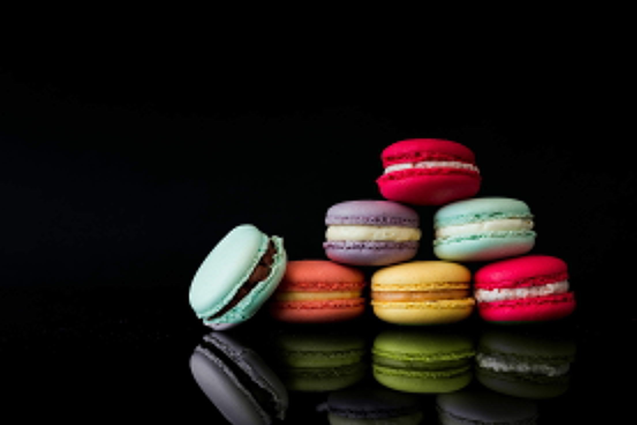 A stack of colorful macarons on a black background - Foodie