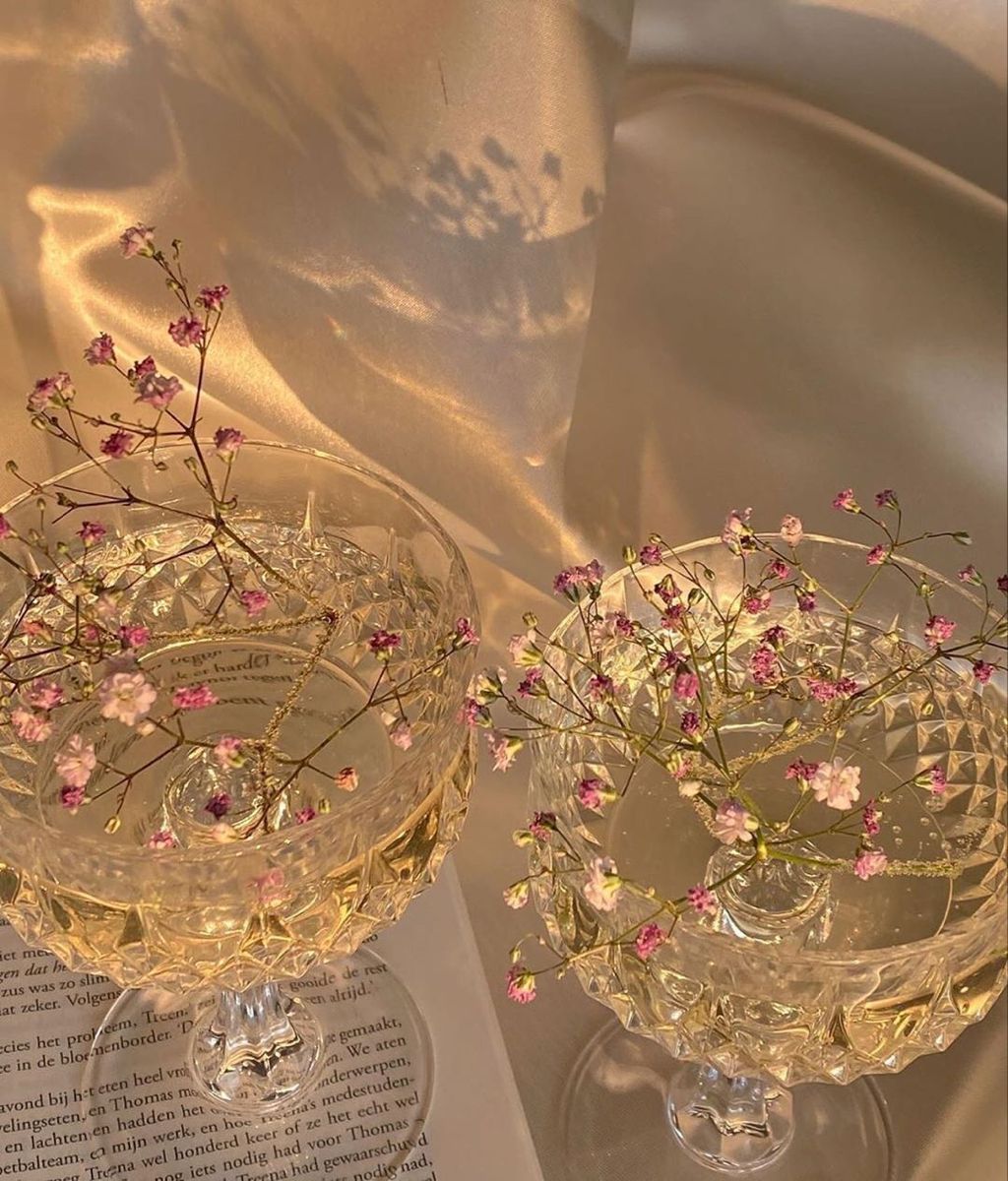 Two wine glasses with flowers in them on a table - Champagne