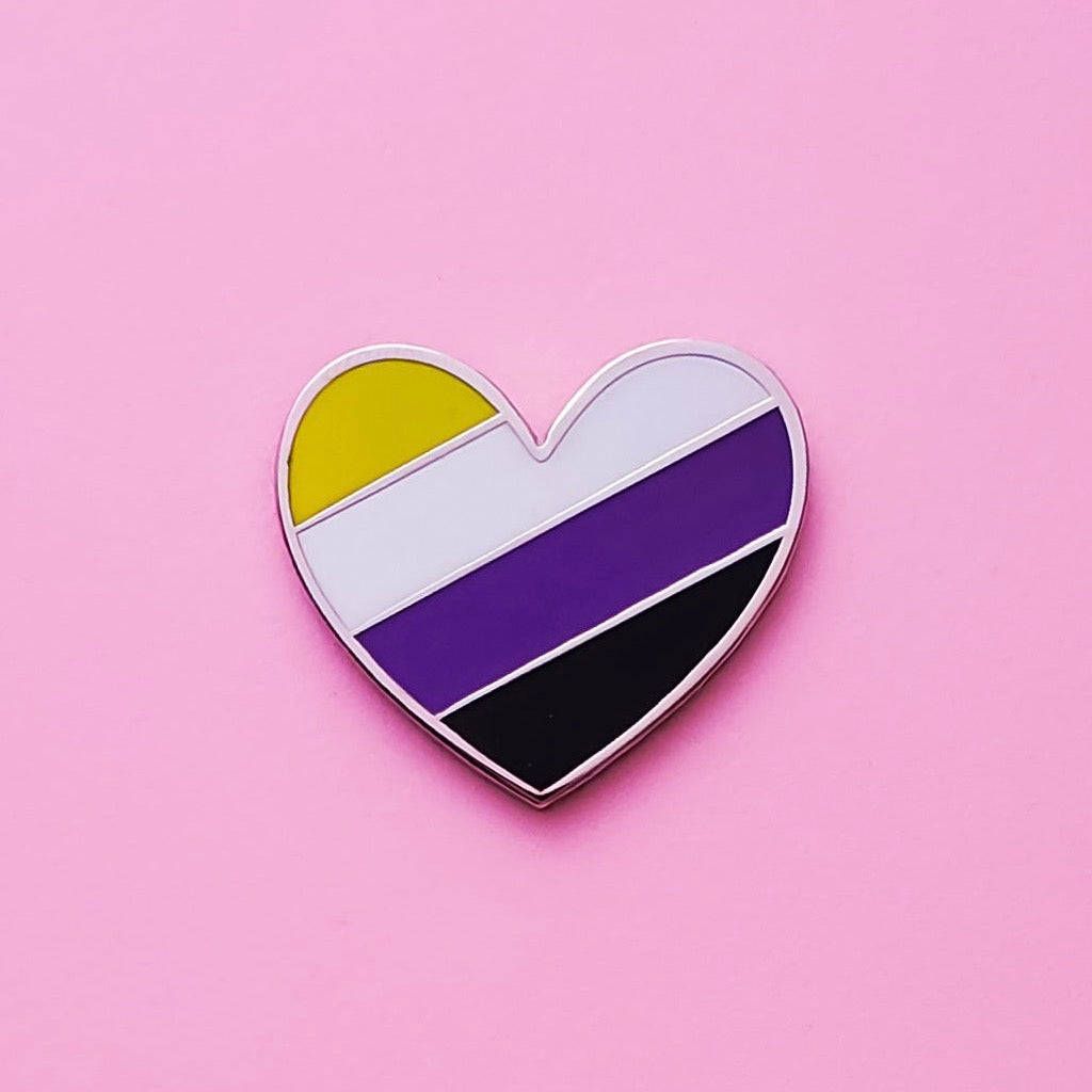 A rainbow heart pin on pink background - Non binary