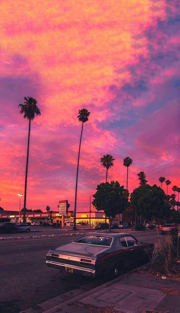 A car parked on the side of the road with a beautiful sunset in the background. - Miami