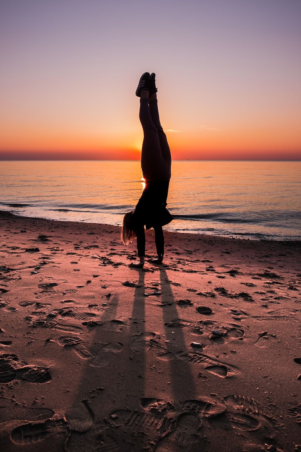 A person doing yoga on the beach at sunset - Gymnastics