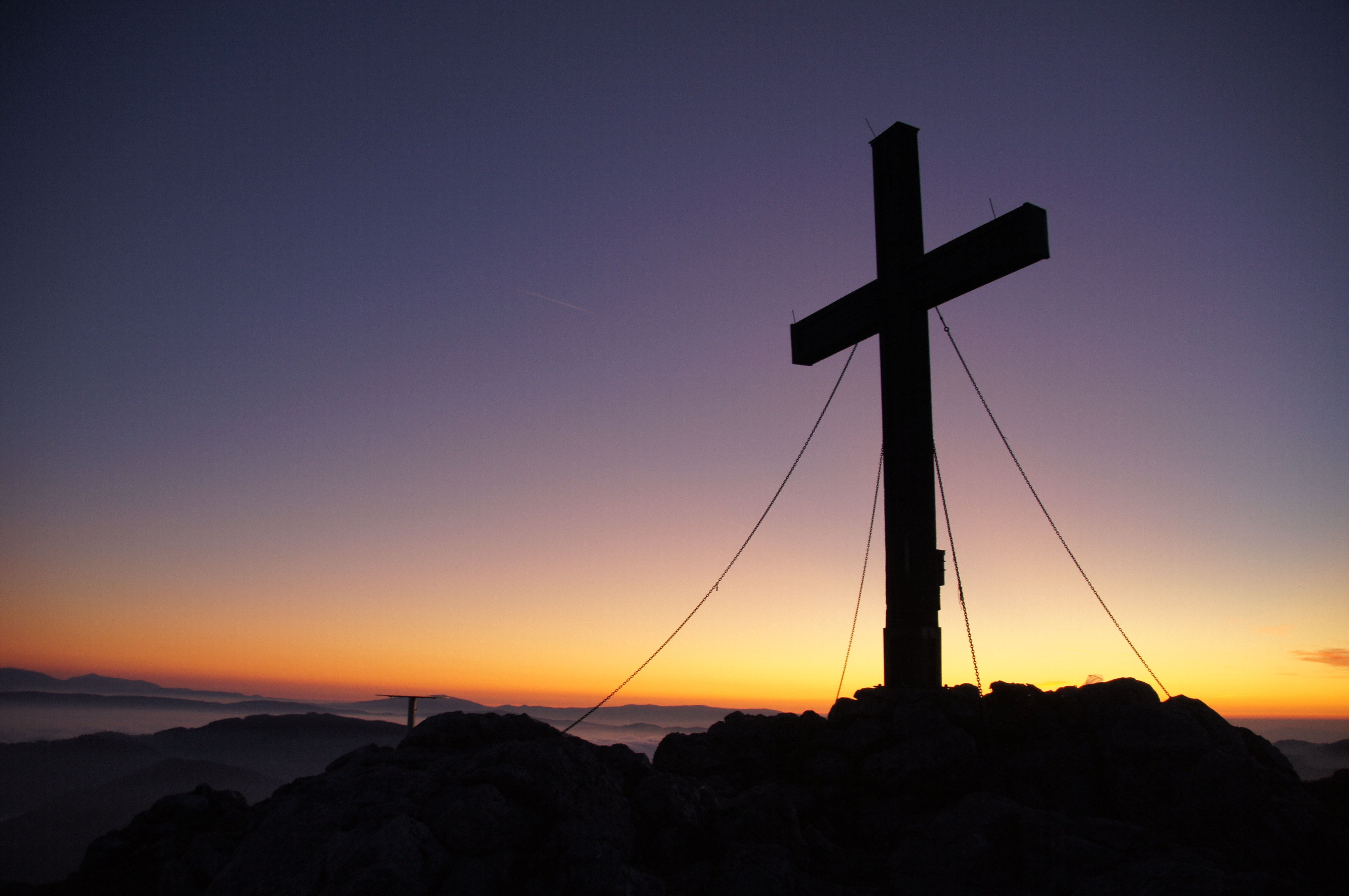 A cross on top of a mountain at sunset. - Cross