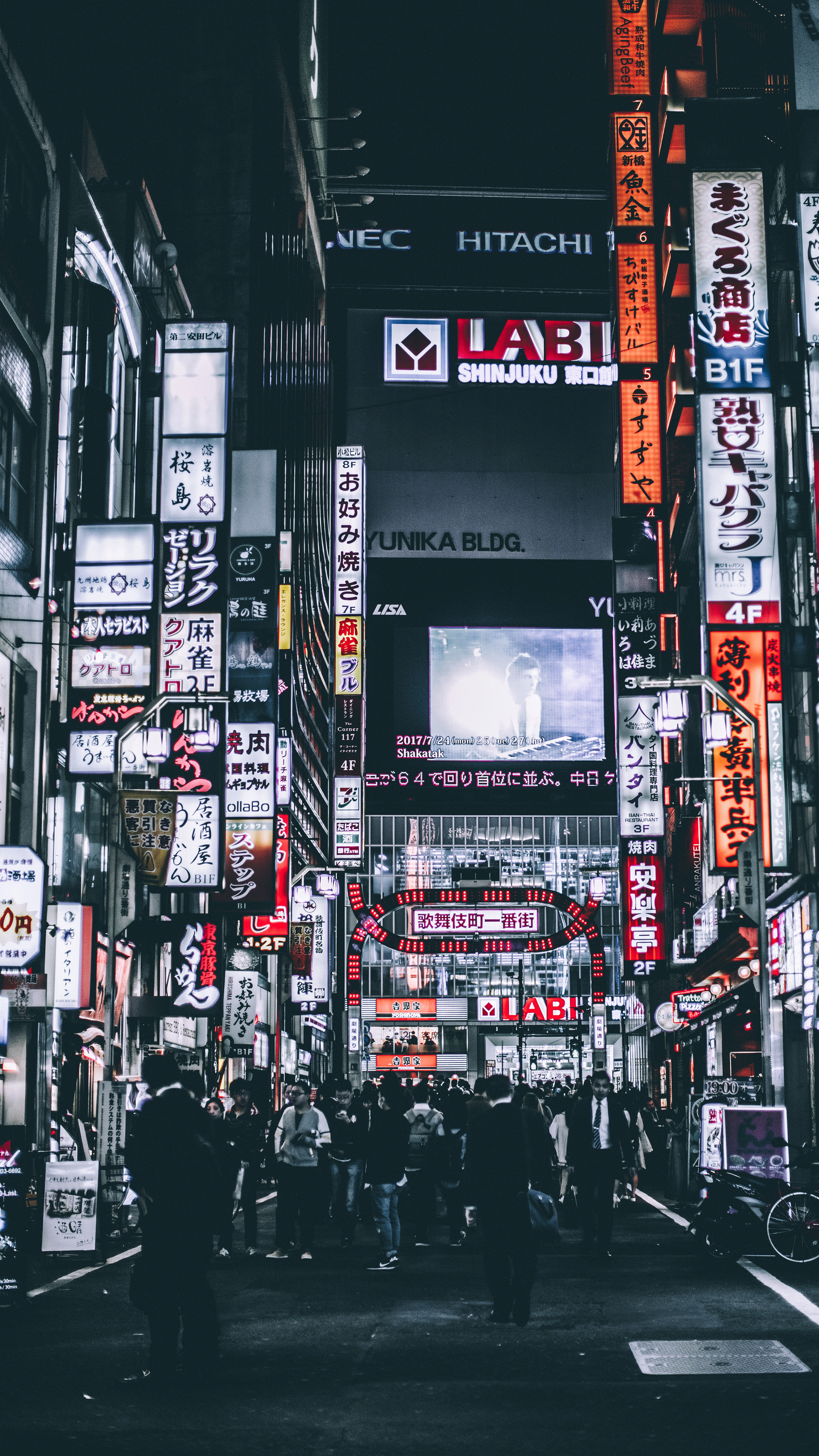 A busy street in Tokyo at night with many people and neon signs. - Tokyo