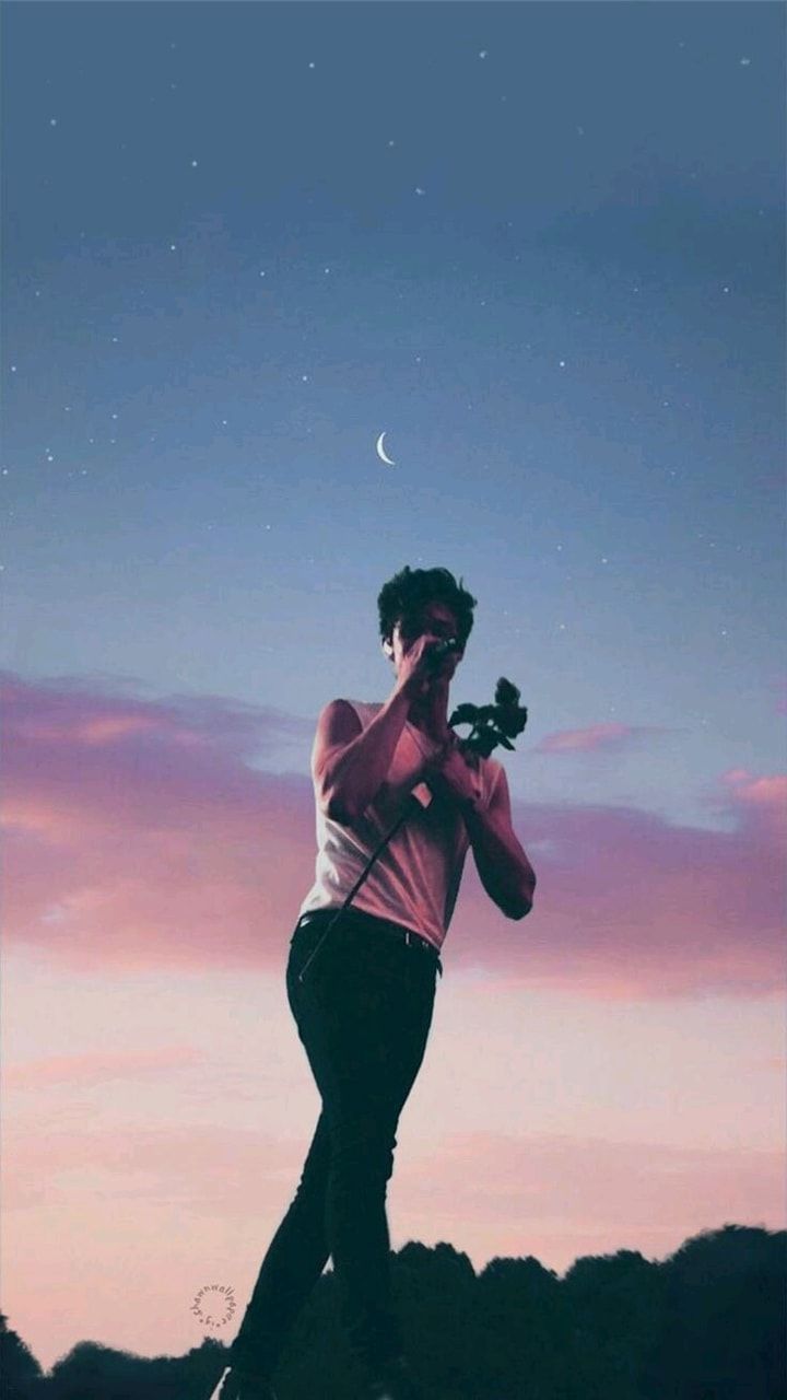 Wallpaper of a man holding a camera with a beautiful sky in the background - Shawn Mendes