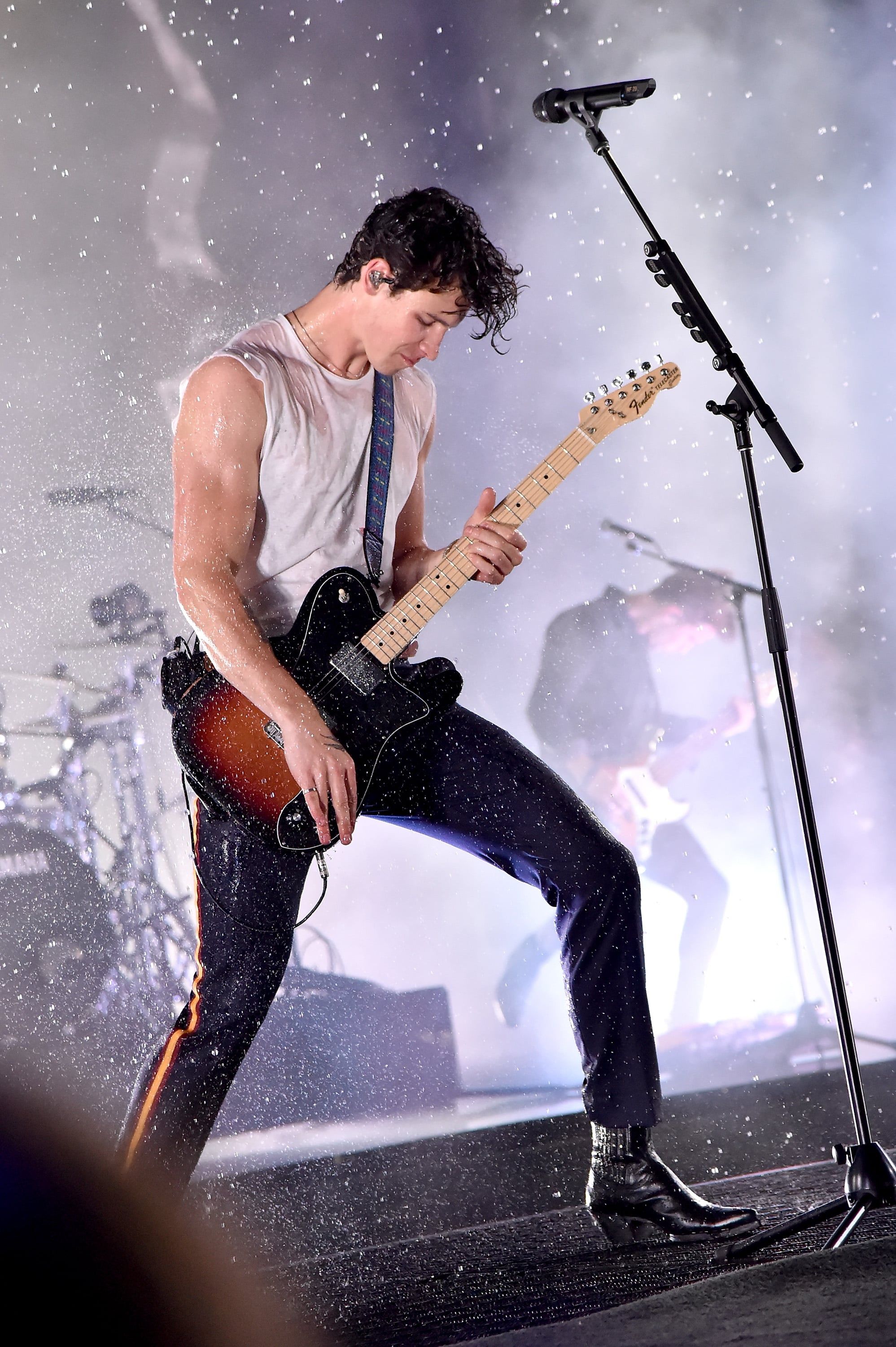 A man playing guitar on stage in front of an audience - Shawn Mendes