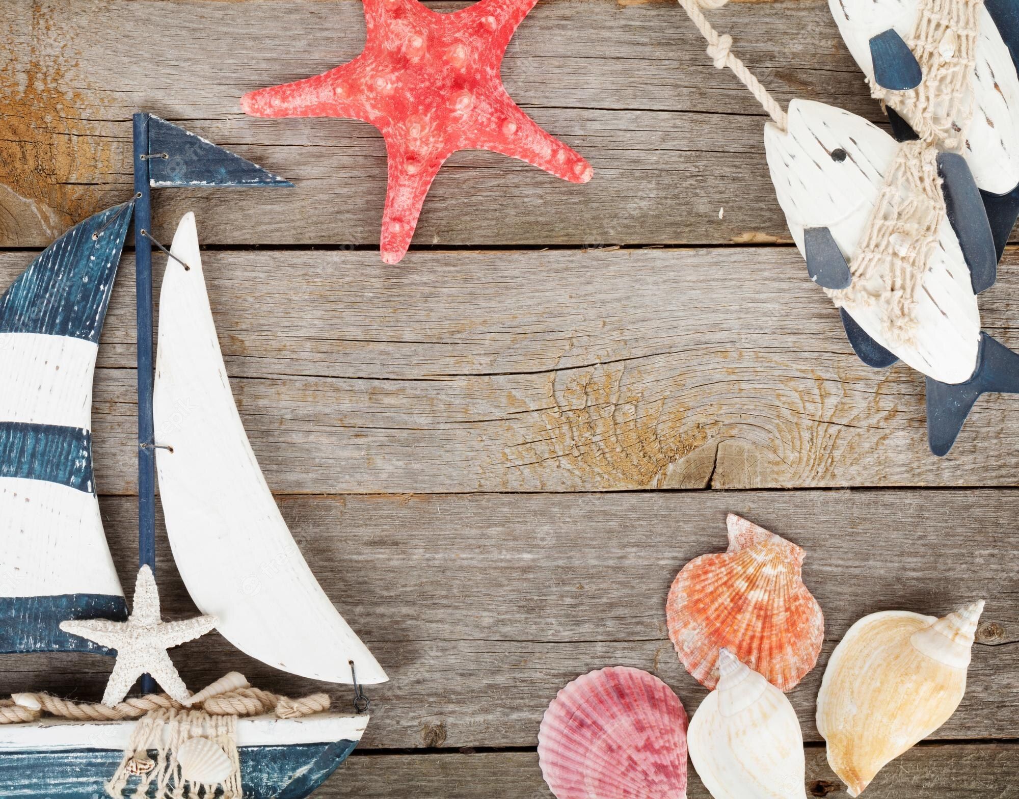 Premium Photo. Toy sailboat and fish with seashells and starfish on a wooden background