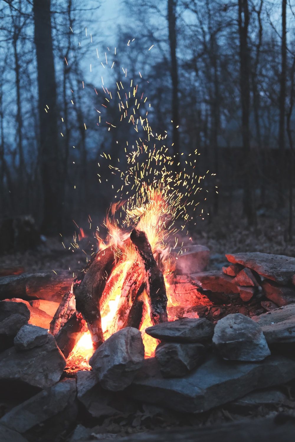 A campfire in the woods with sparks flying - Camping