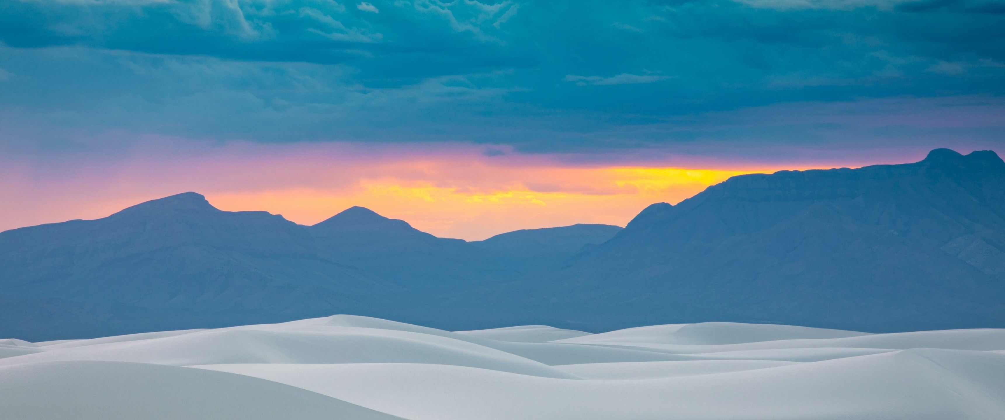 A colorful sunset over the sand dunes in White Sands National Monument. - 3440x1440