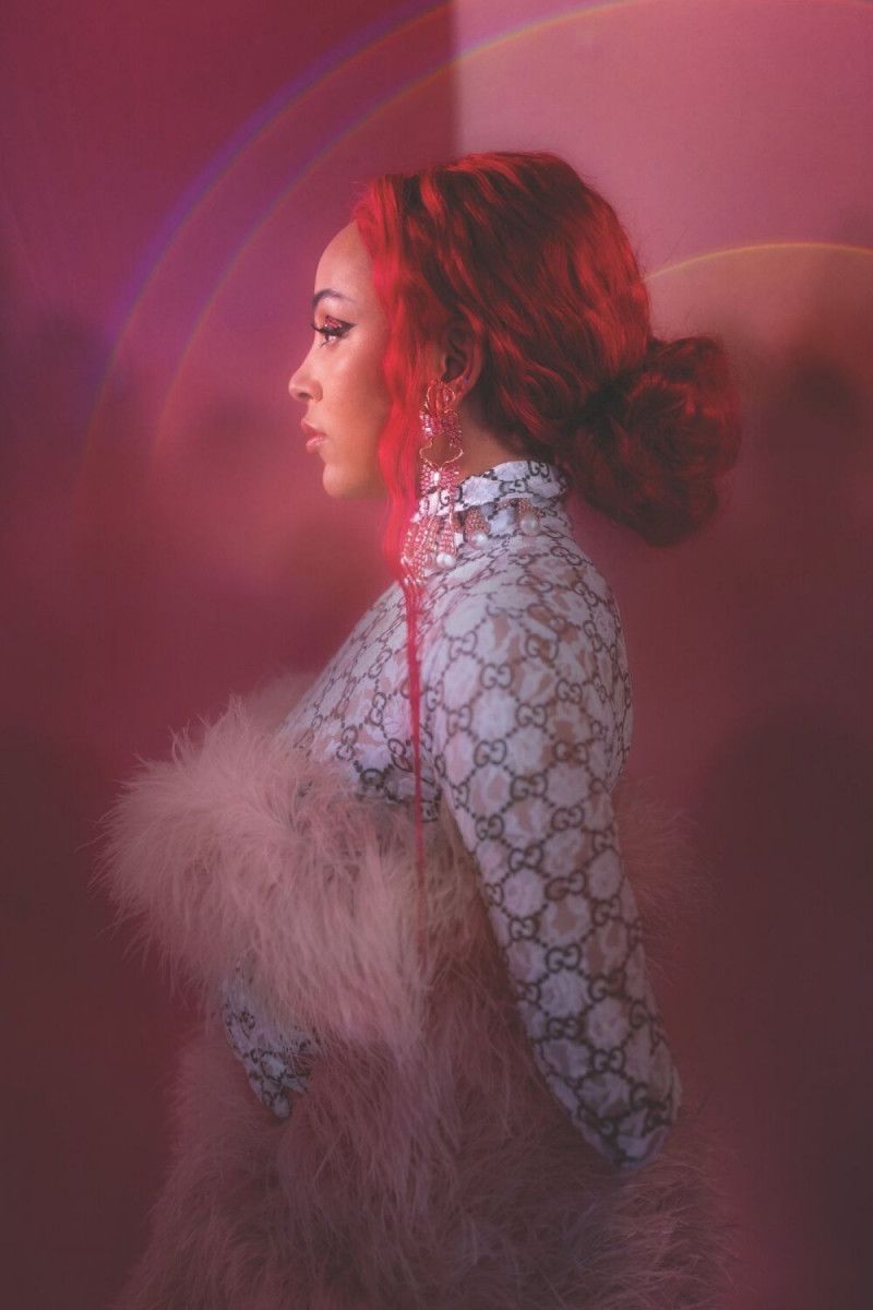 A woman with red hair in a white top with a feather boa. - Doja Cat