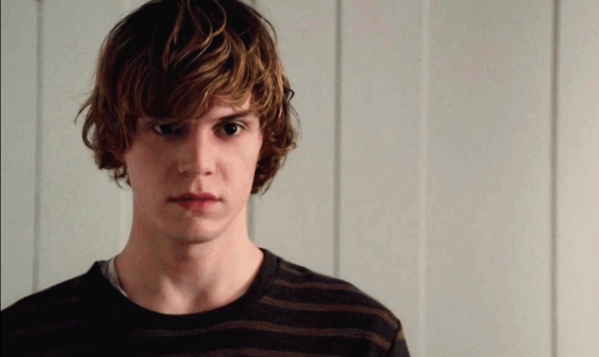 Evan Peters as Tate in 'American Horror Story: Murder House'. He is wearing a black and brown striped shirt and looking at the camera. - Evan Peters