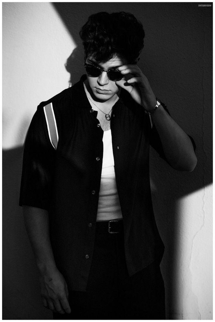 A man in sunglasses and shirt leaning against the wall - Evan Peters