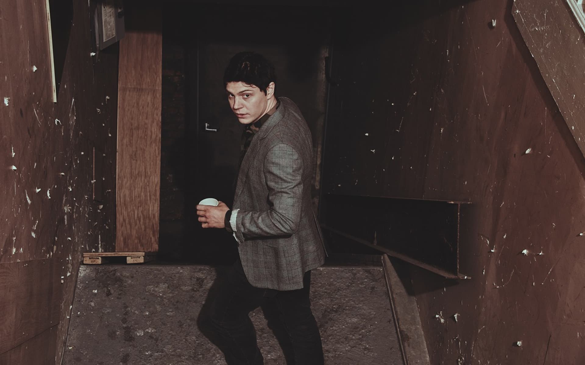 A man in suit and tie holding coffee cup - Evan Peters