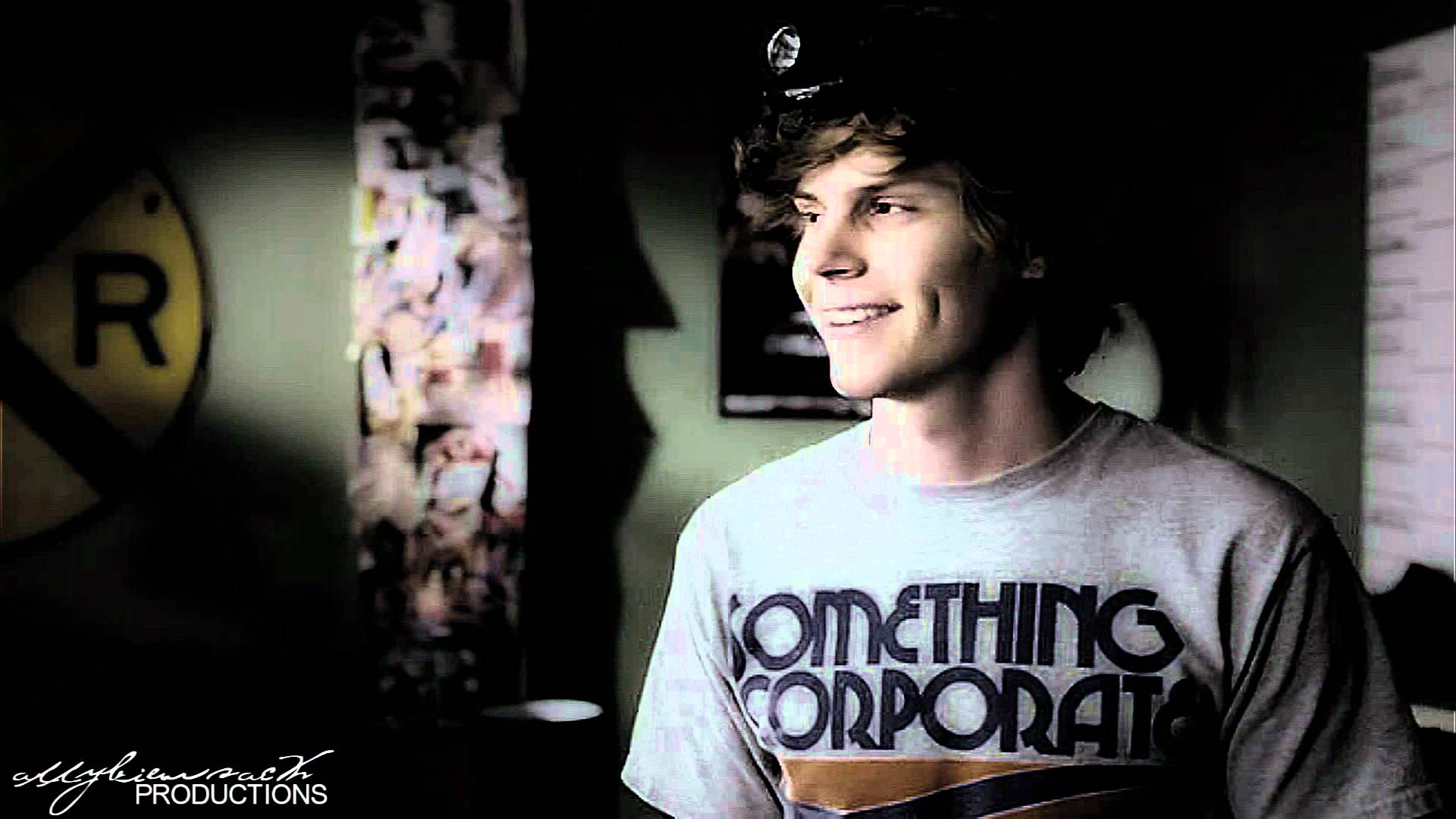 A young man wearing a grey shirt with the words something corporate on it. - Evan Peters