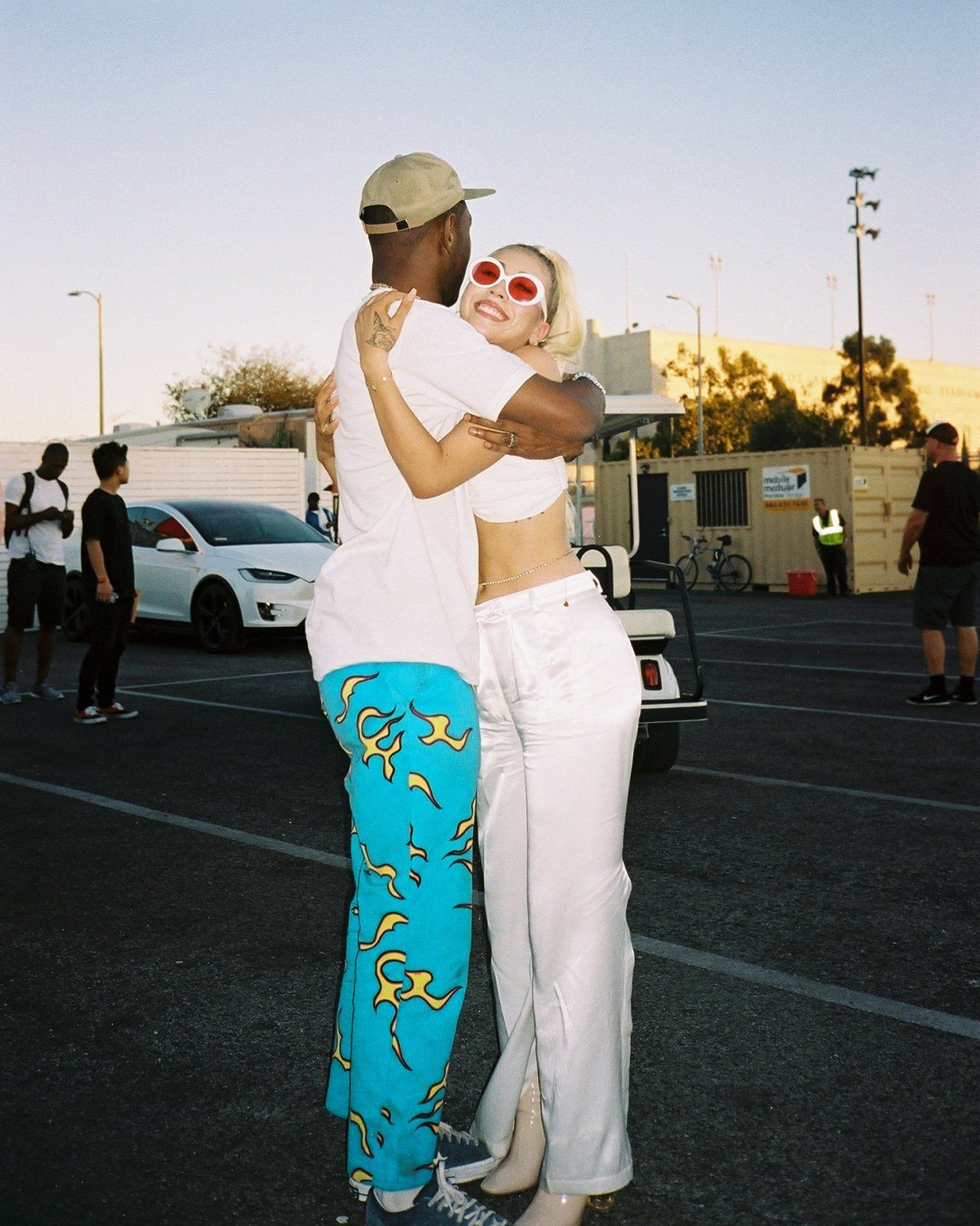 A couple of people hugging in the parking lot - Kali Uchis