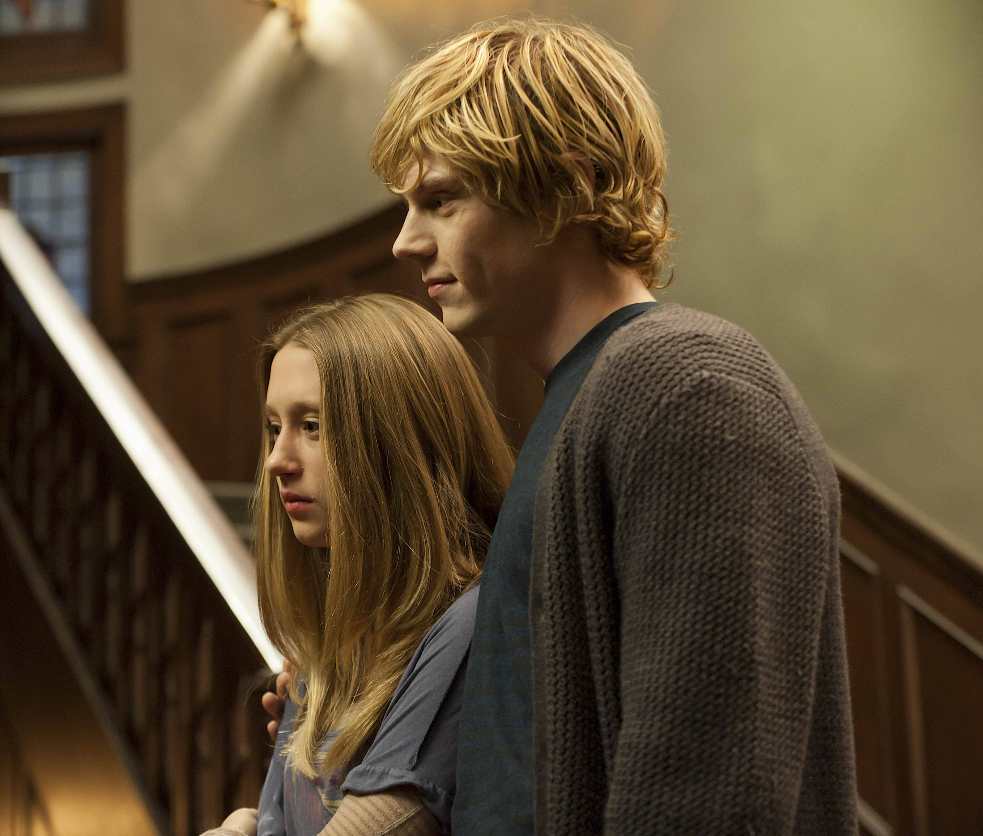 A man and woman standing together in front of stairs - Evan Peters