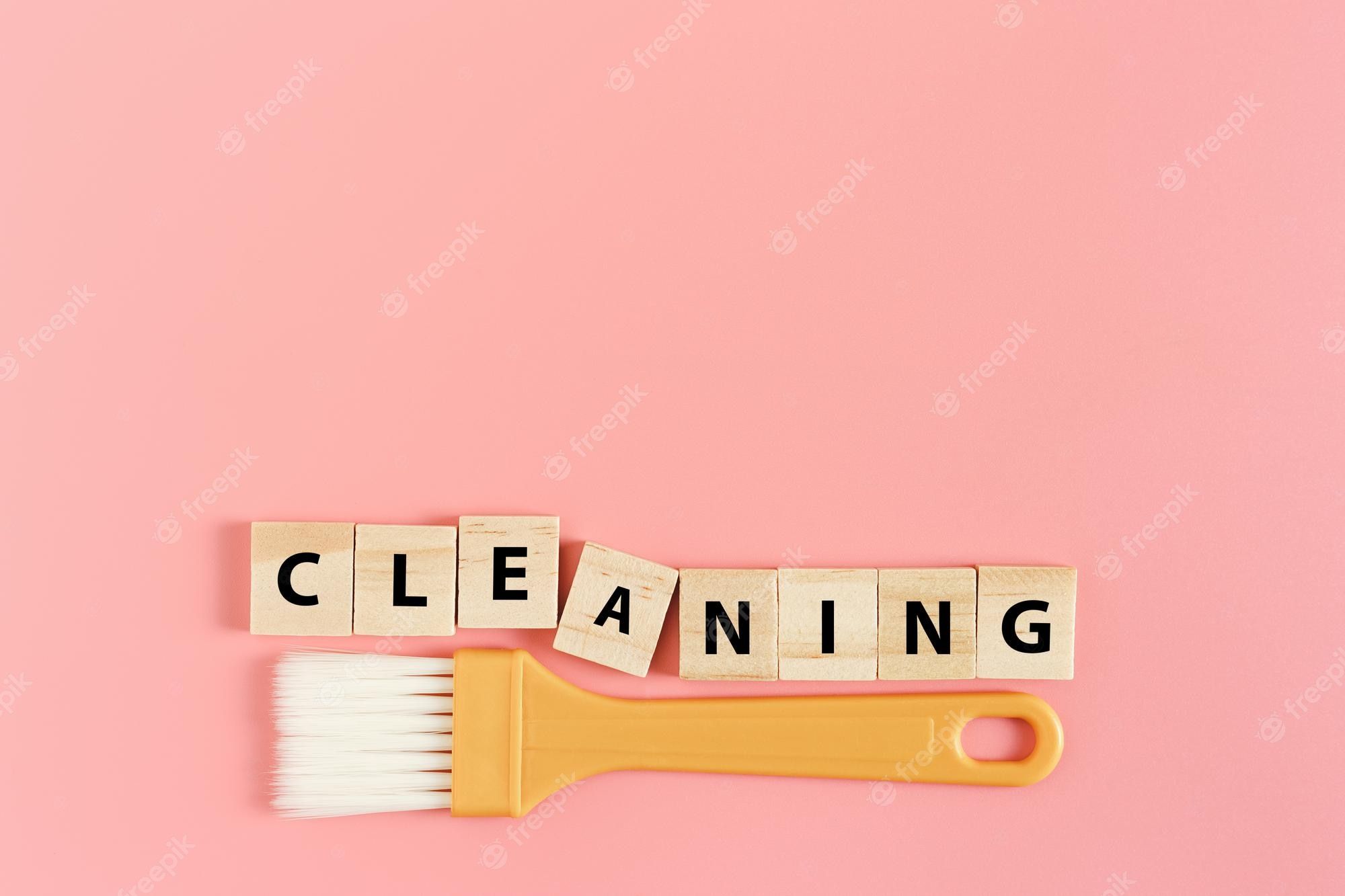 Premium Photo. Word text cleaning on wooden cube with dust brush on pink background
