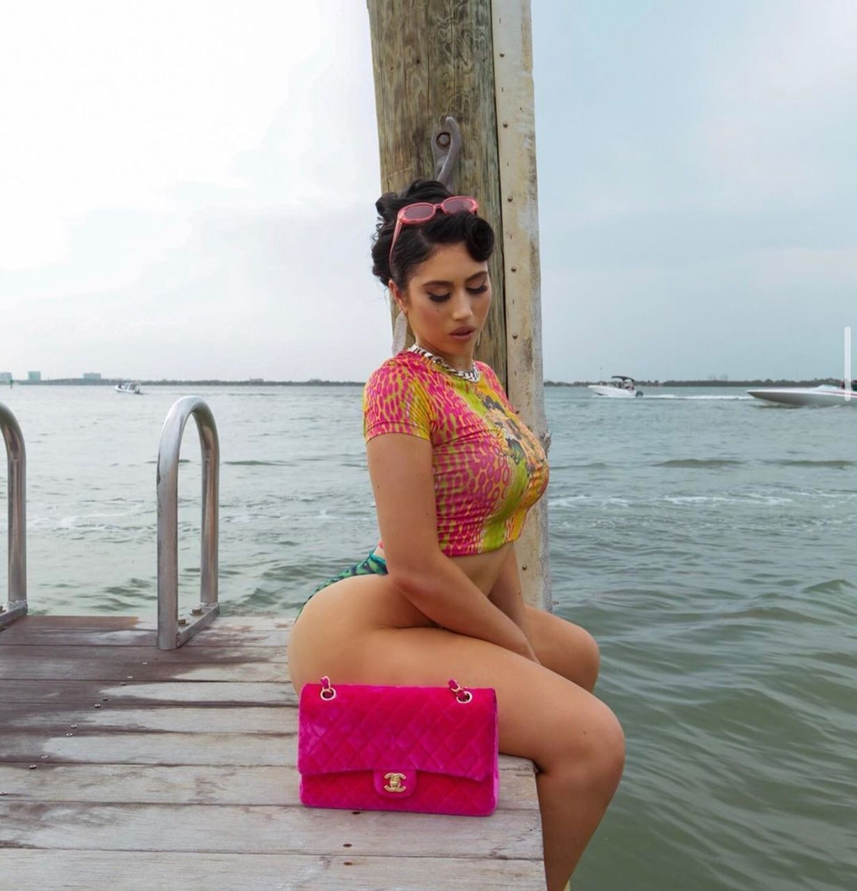 A woman sitting on the dock with her purse - Kali Uchis