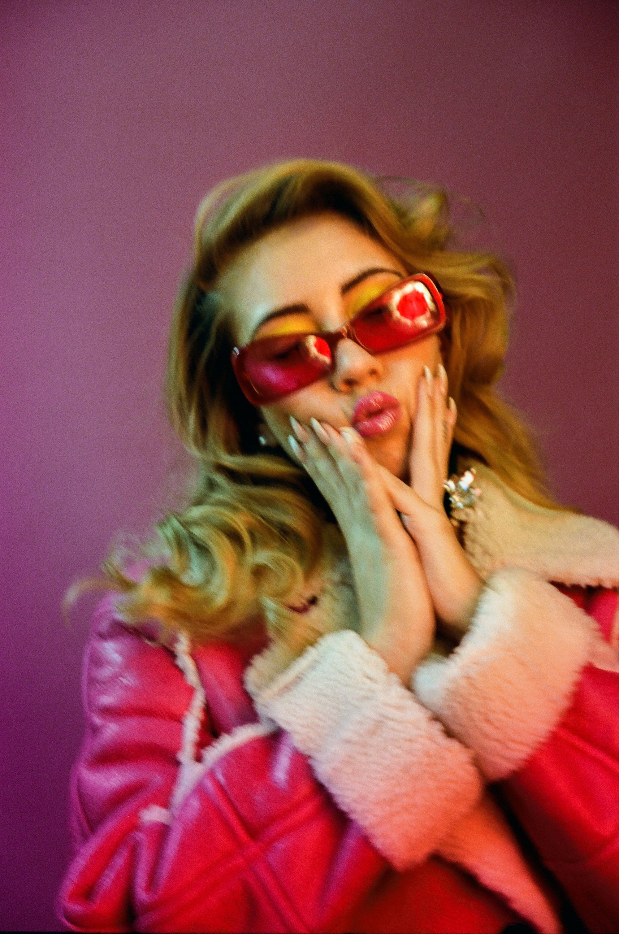 A woman in red coat and sunglasses - Kali Uchis