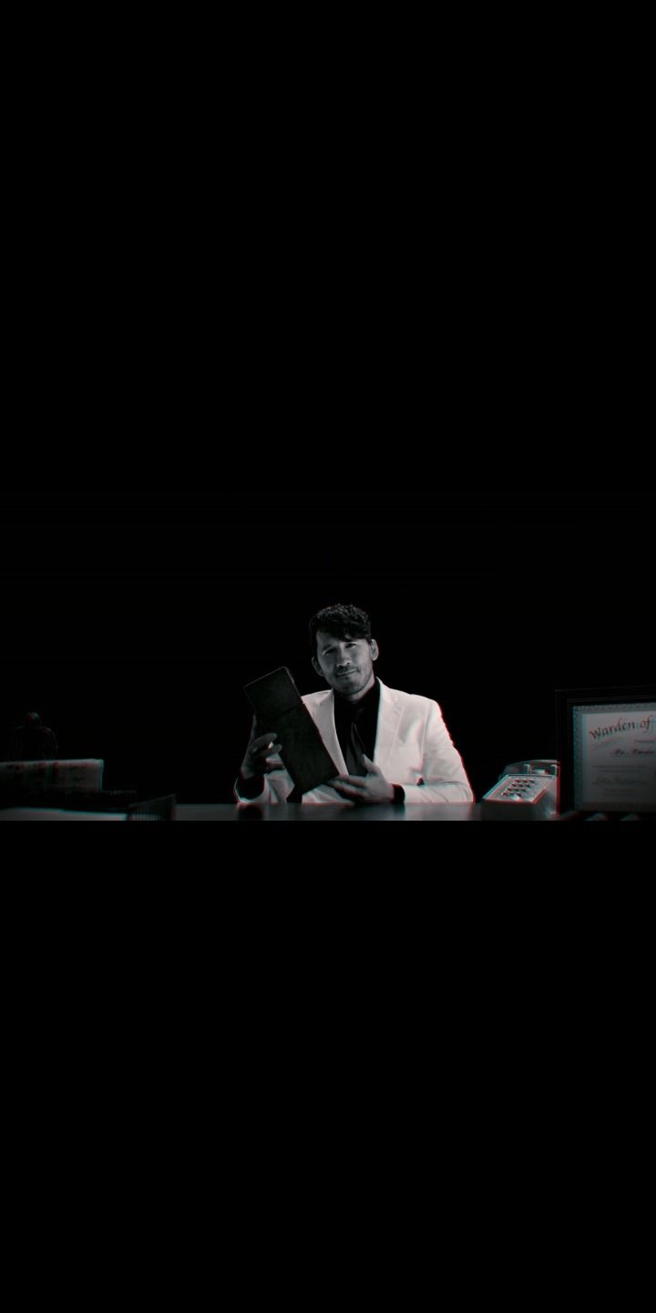 A man in a white suit sitting at a desk reading a book - Markiplier