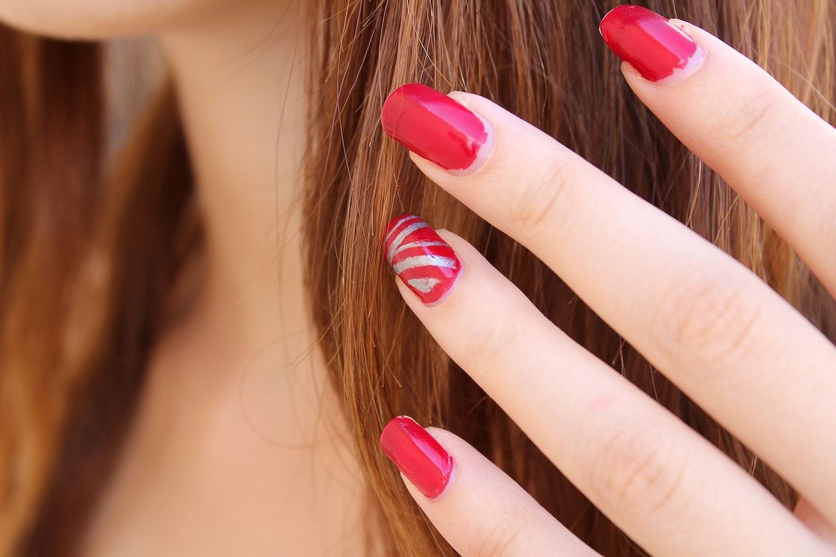 A woman with red and white striped nails. - Nails