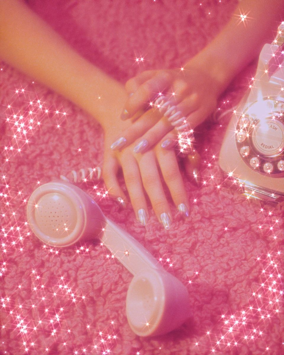 A woman with pink nails and rings holding onto an old phone - Nails