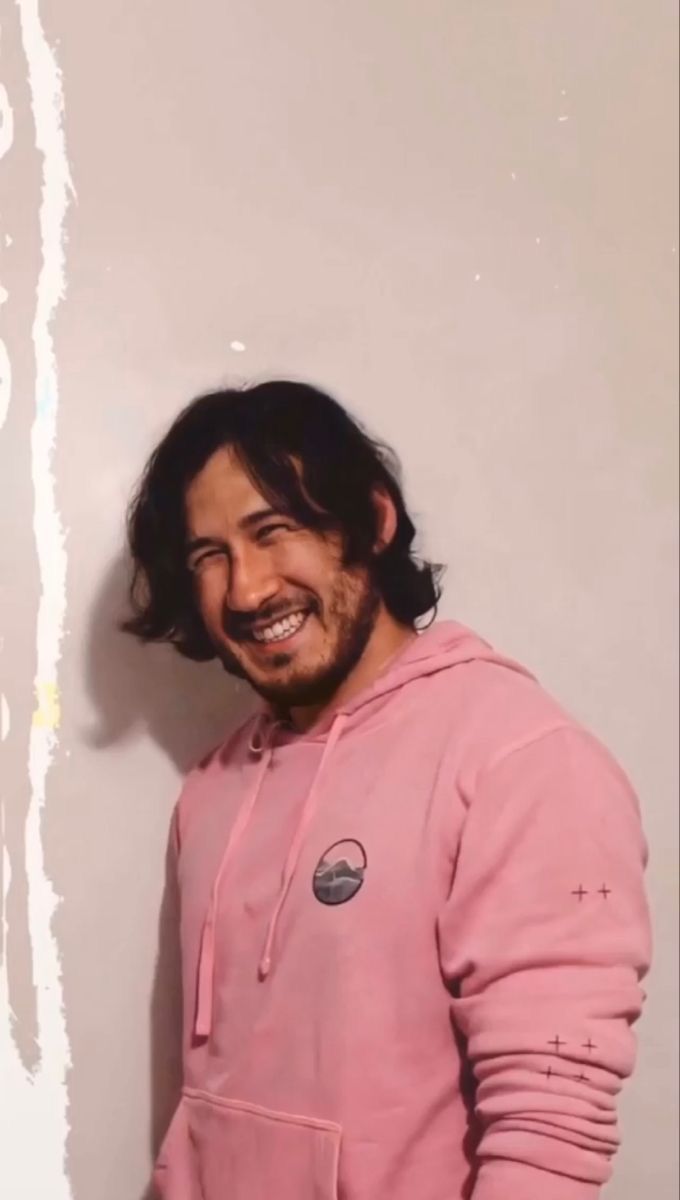 A man in a pink hoodie smiling. - Markiplier