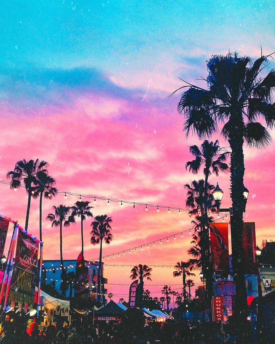 A colorful sunset over the beach with palm trees - California