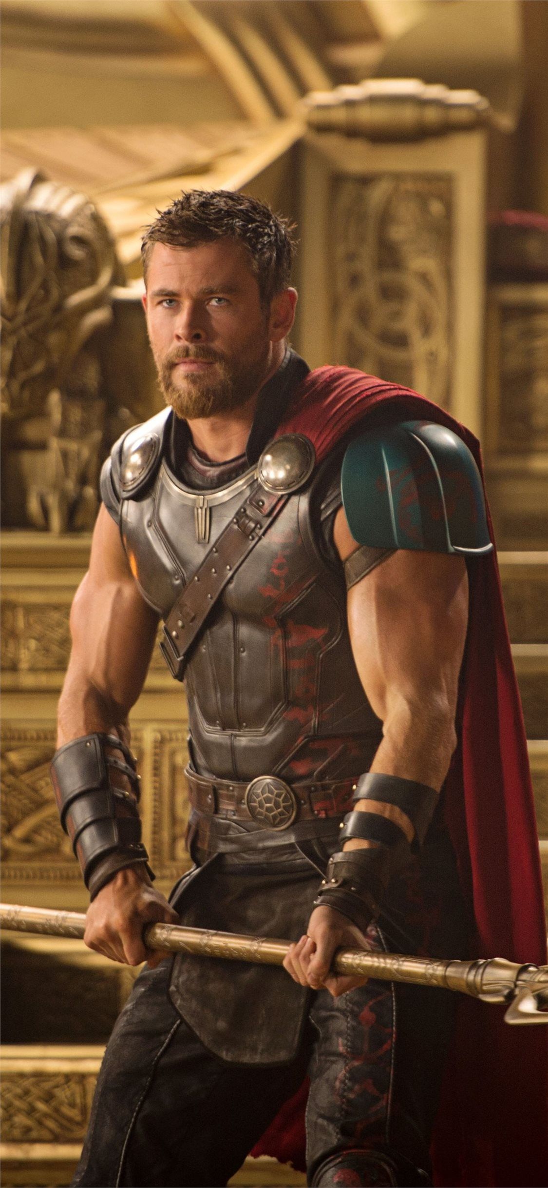 Chris Hemsworth as Thor in Thor: Ragnarok, standing in a golden hall with a red cape and a big hammer - Thor